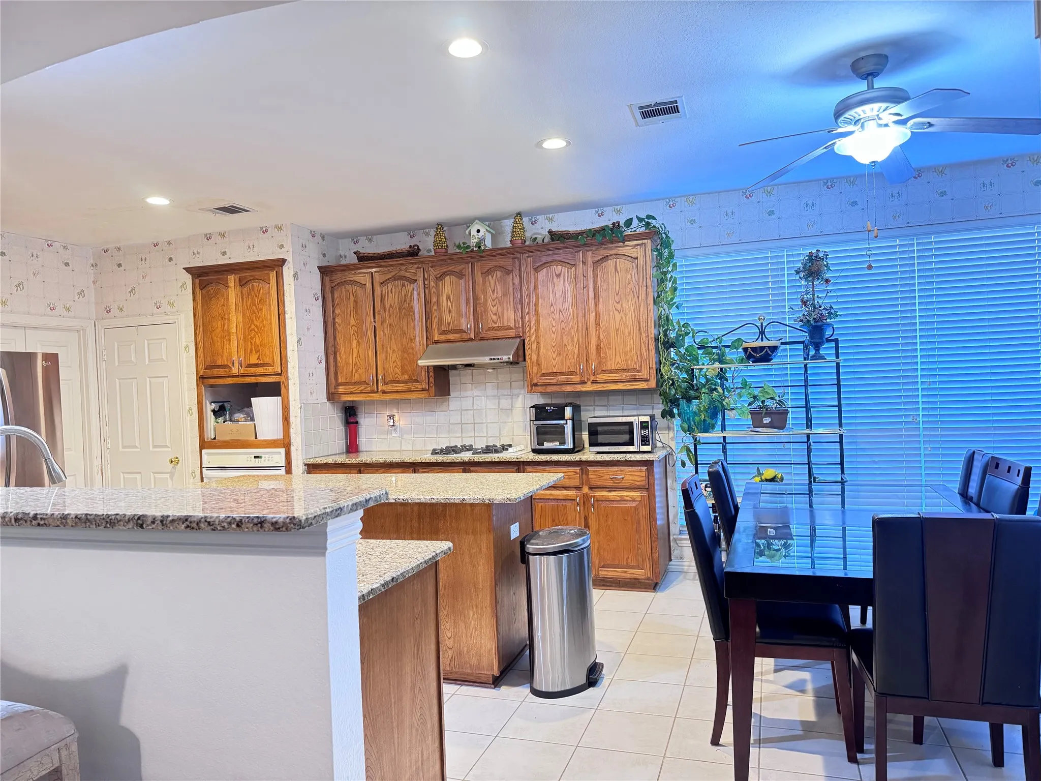Kitchen featuring wood cabinetry, granite-finish countertops, and a tile backsplash