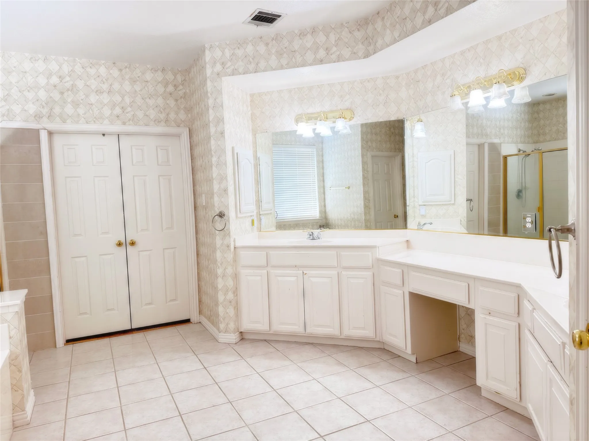 Bathroom featuring dual vanities with white cabinetry, integrated sinks, and expansive mirrors