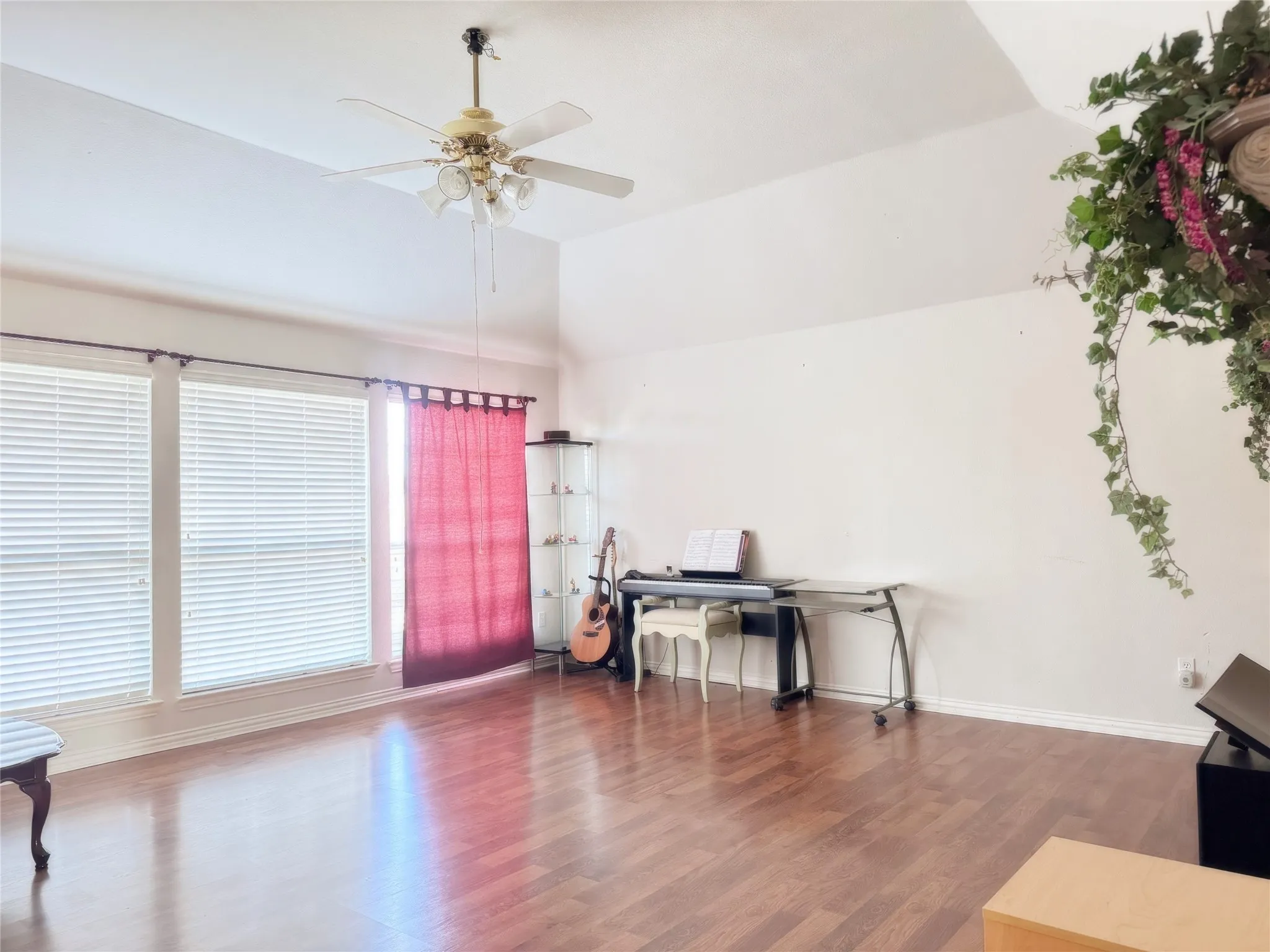 Spacious room featuring vaulted ceilings, wood-finish flooring, and multiple windows