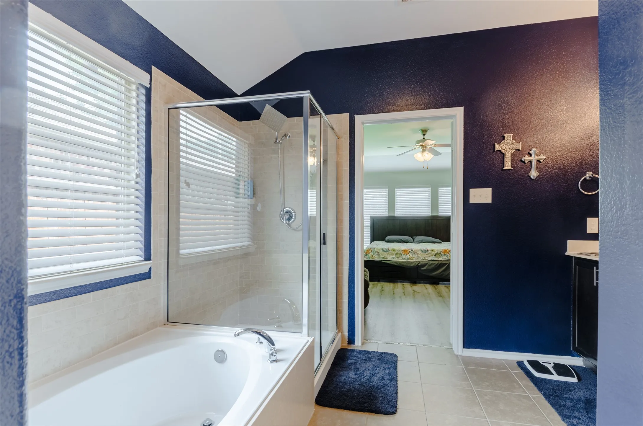 Bathroom featuring a built-in soaking tub, a glass-enclosed shower, and neutral tile flooring