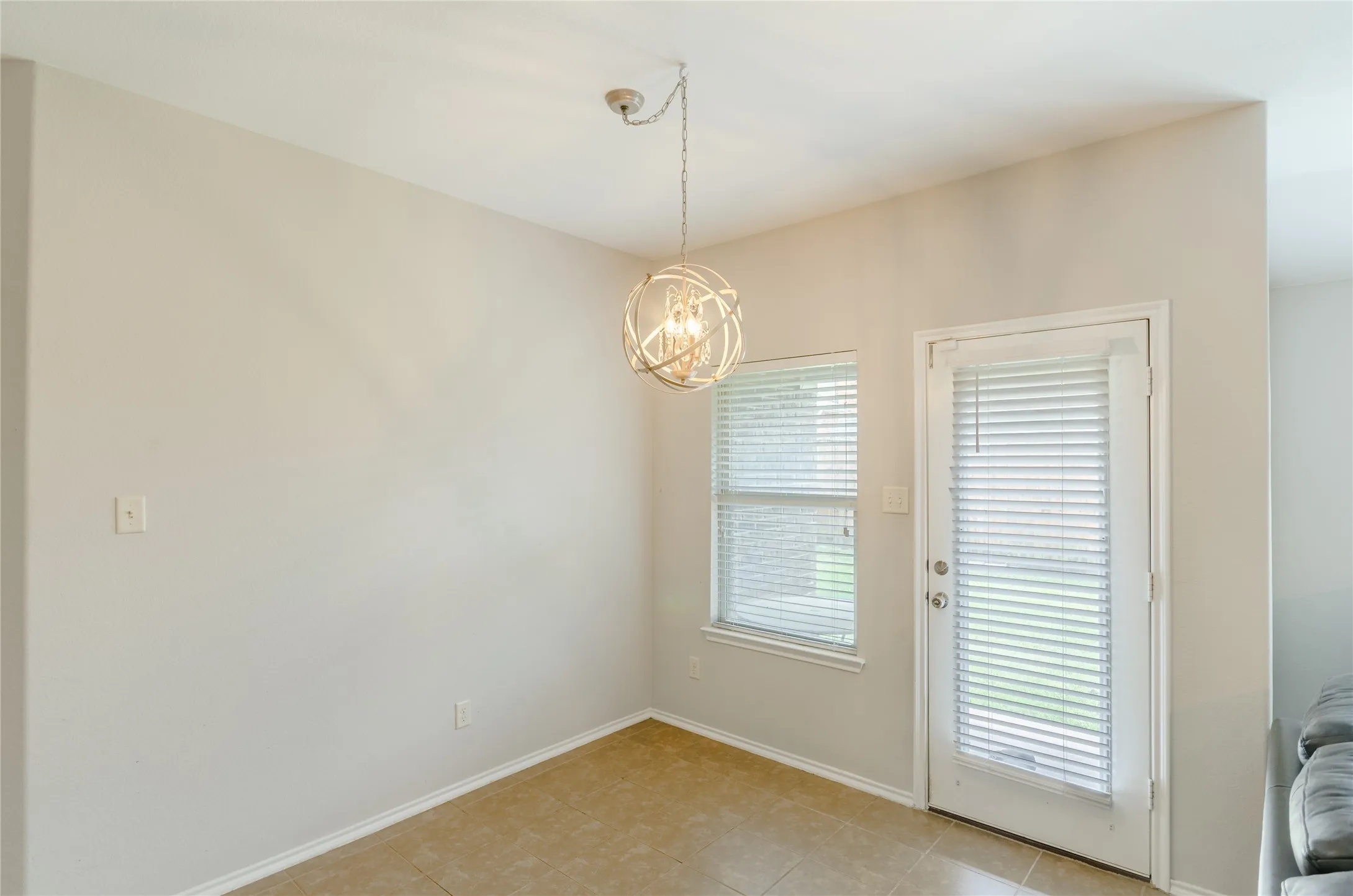Breakfast area featuring a contemporary spherical chandelier, neutral wall paint, and tile flooring