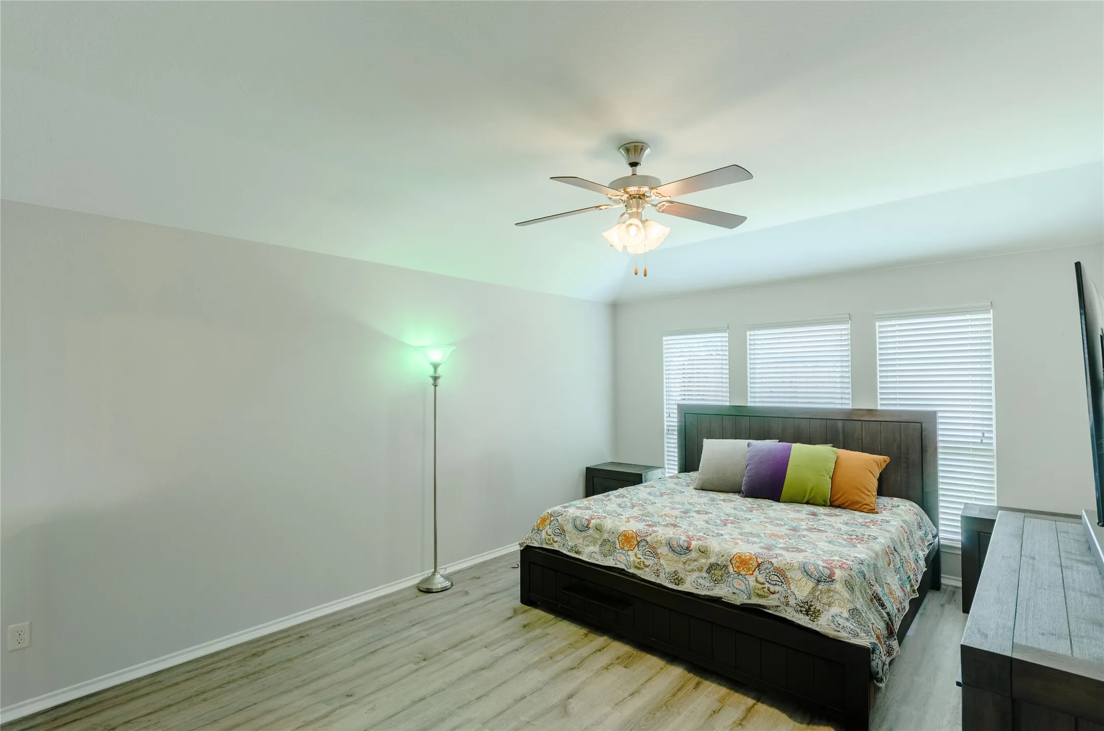 Spacious room with wood-finish flooring, vaulted ceiling, and a ceiling fan with integrated lighting