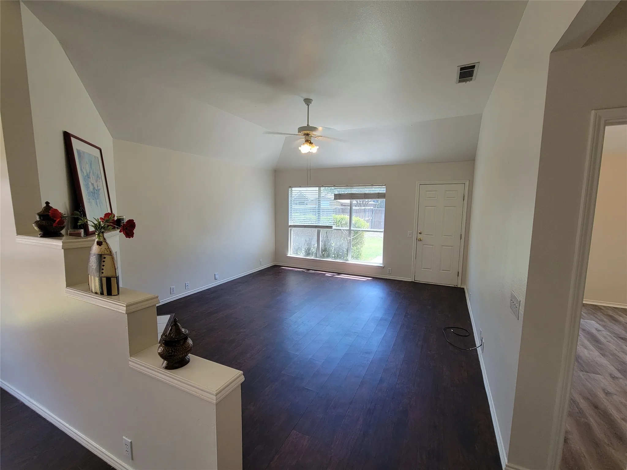 Living room with a fireplace, dark wood-style floors, ceiling fan, and lofted ceiling