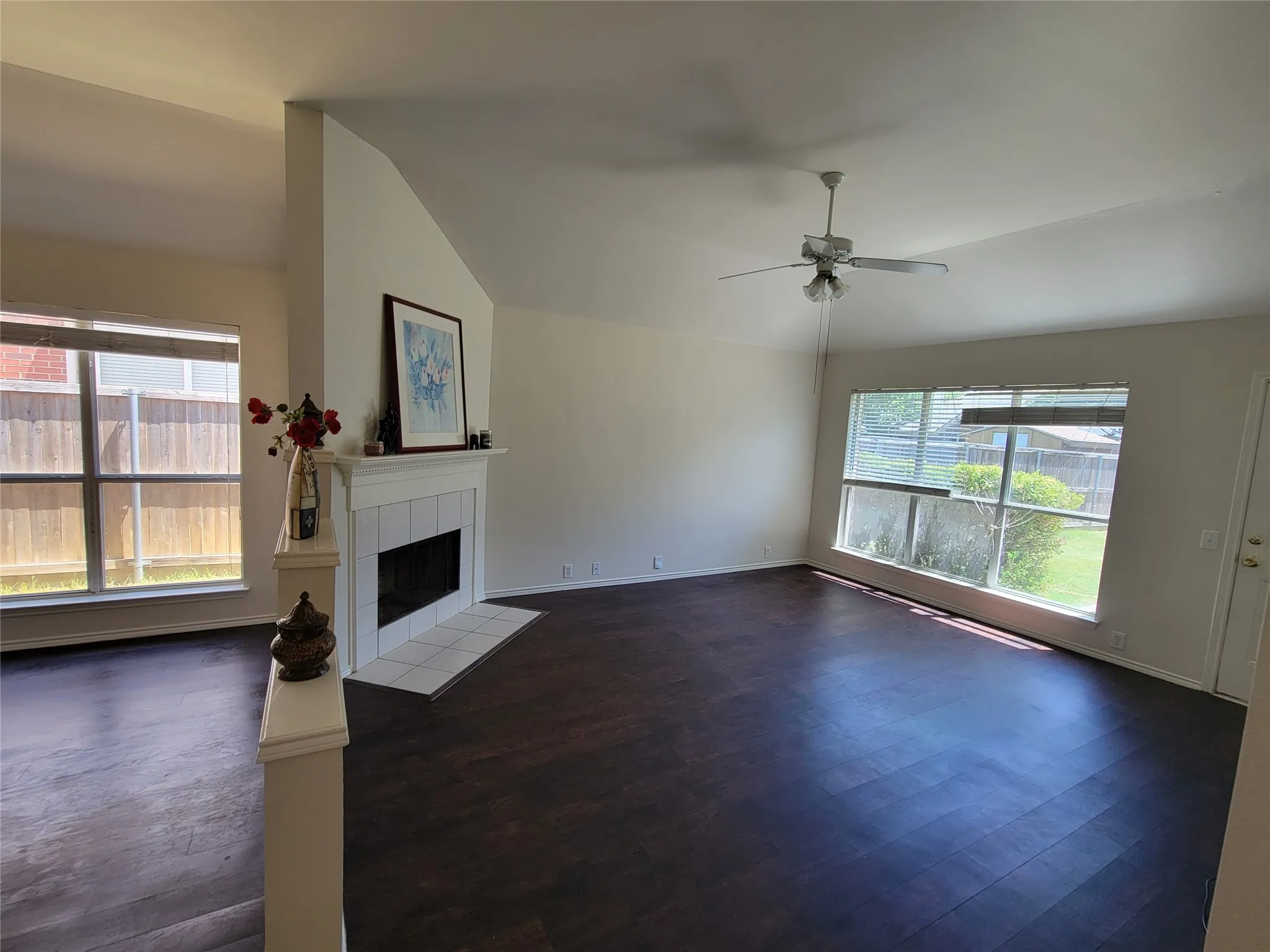 Living room with a fireplace, dark wood-style floors, ceiling fan, and lofted ceiling