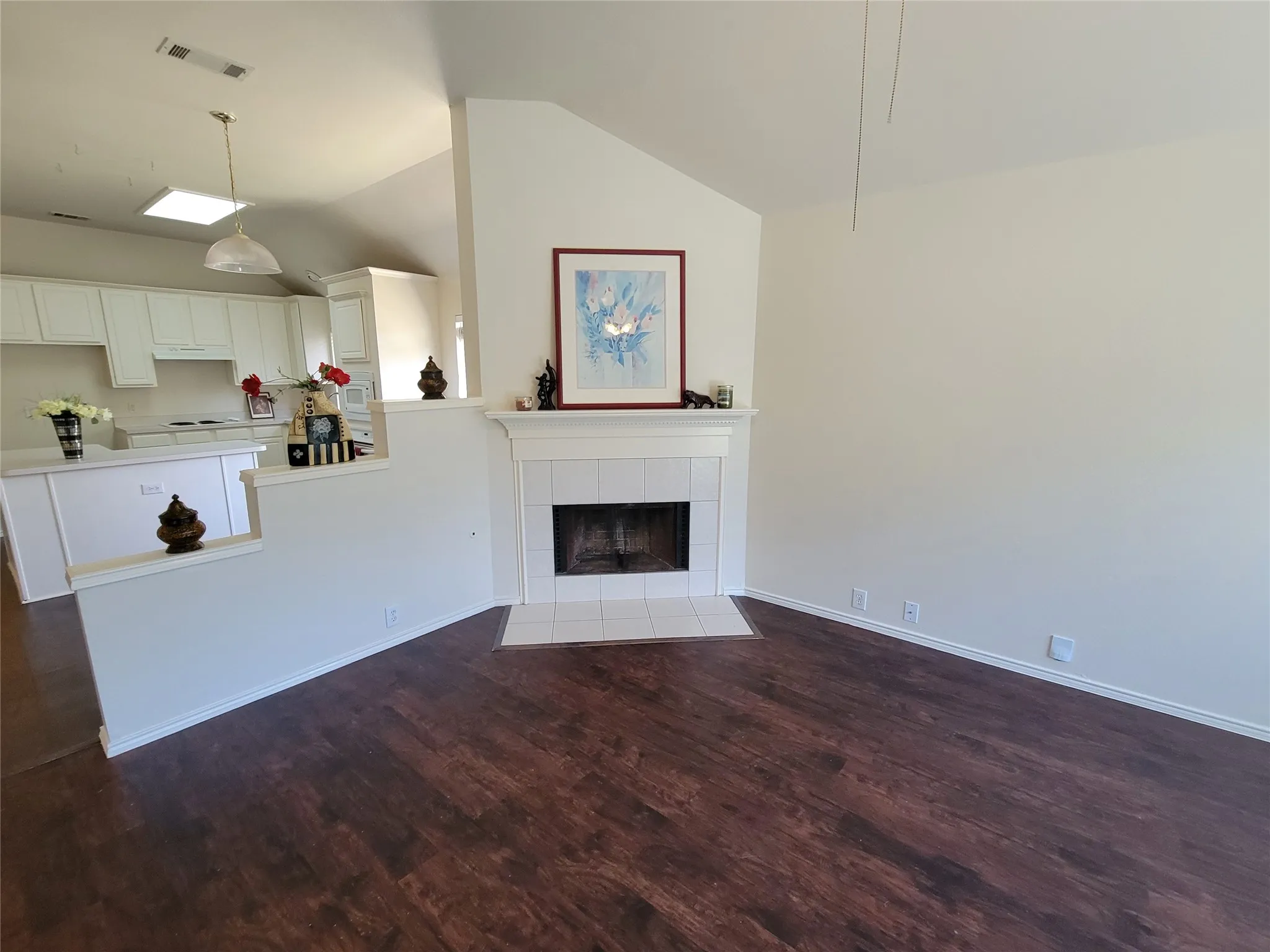 Living room with a fireplace, dark wood-style floors, ceiling fan, and lofted ceiling