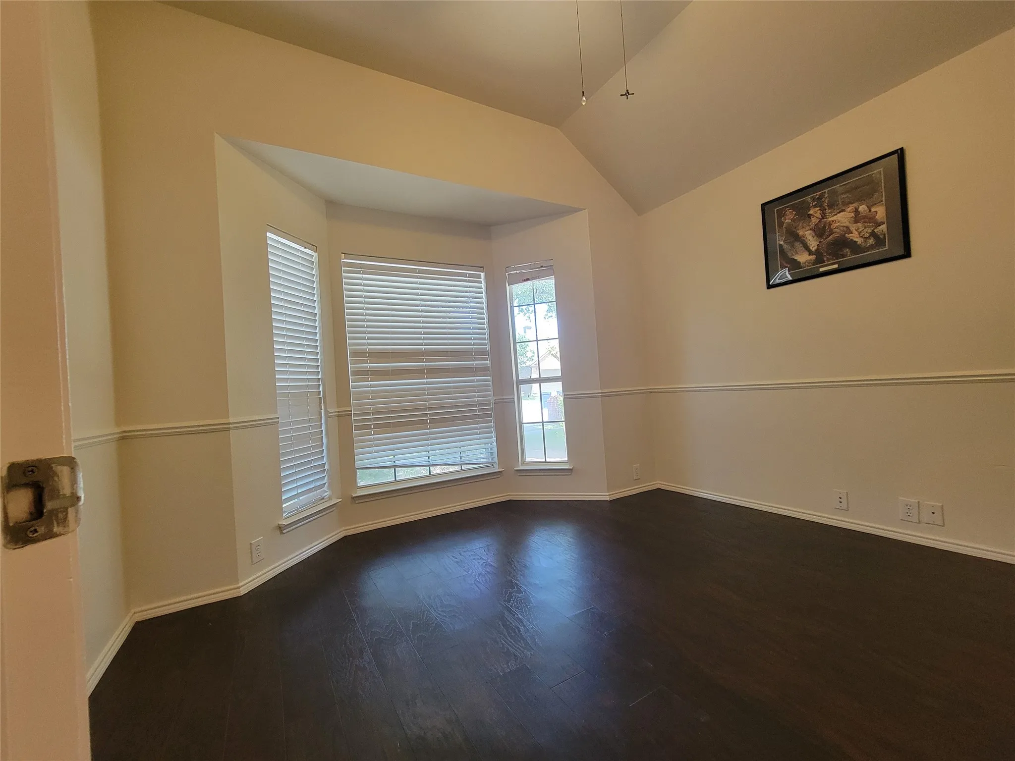 Office with bay window, glass door, and dark wood-style floors, ceiling fan, and lofted ceiling