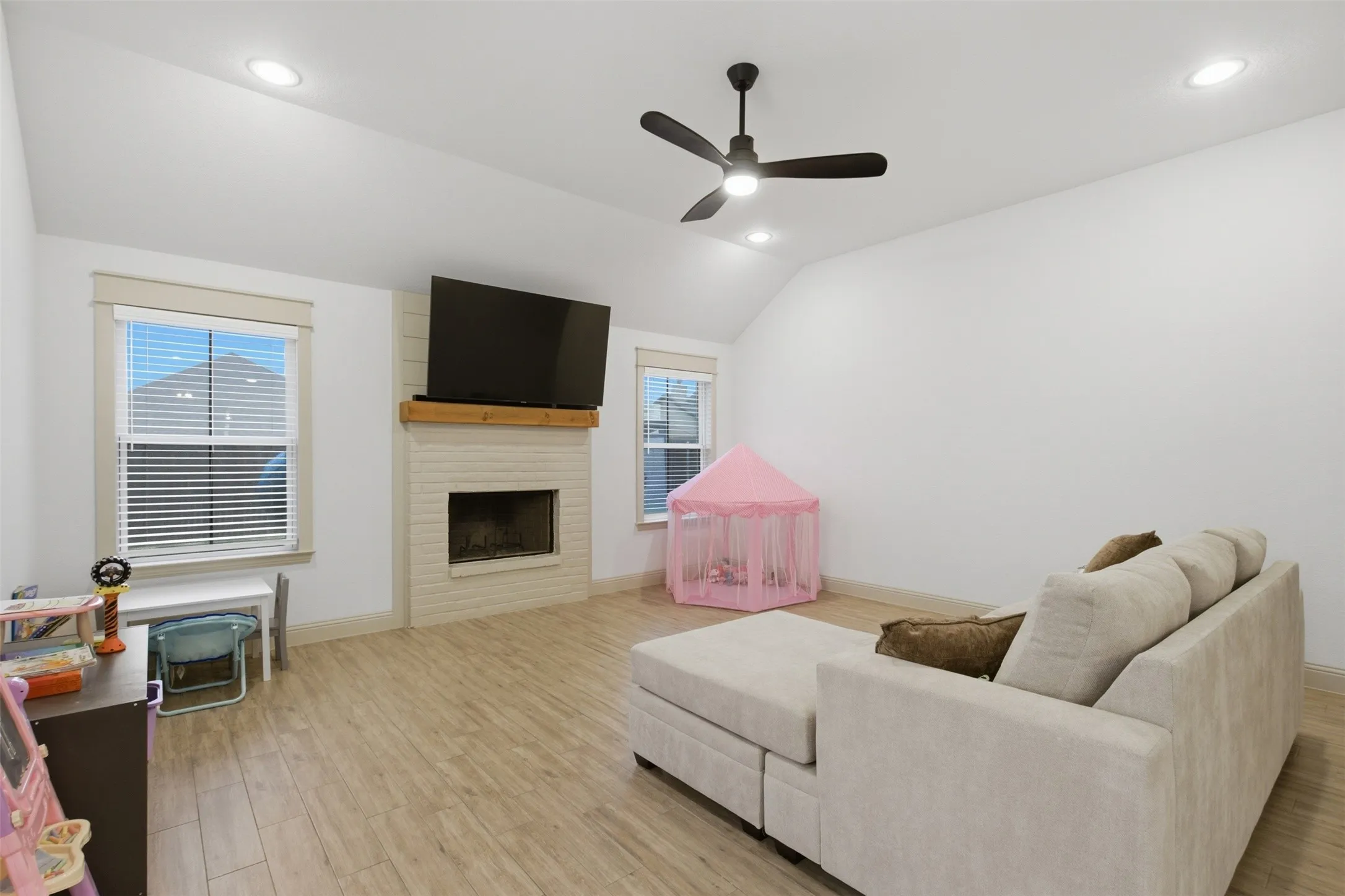 Living area featuring a painted brick fireplace with a wood mantel, wood-finish flooring, and recessed lighting