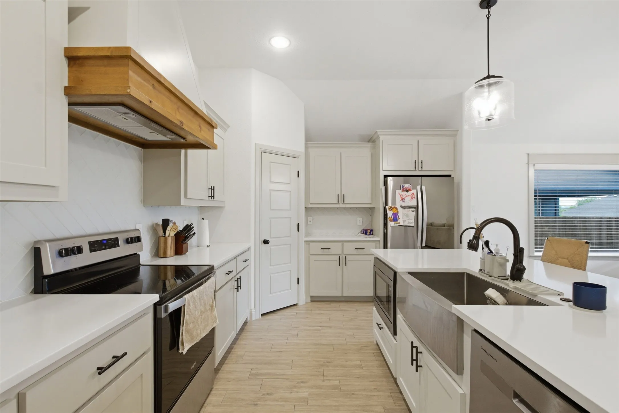 Gourmet kitchen featuring white cabinetry, light-toned countertops, and a fabulous deep set stainless farm style sink! You will love using this kitchen!