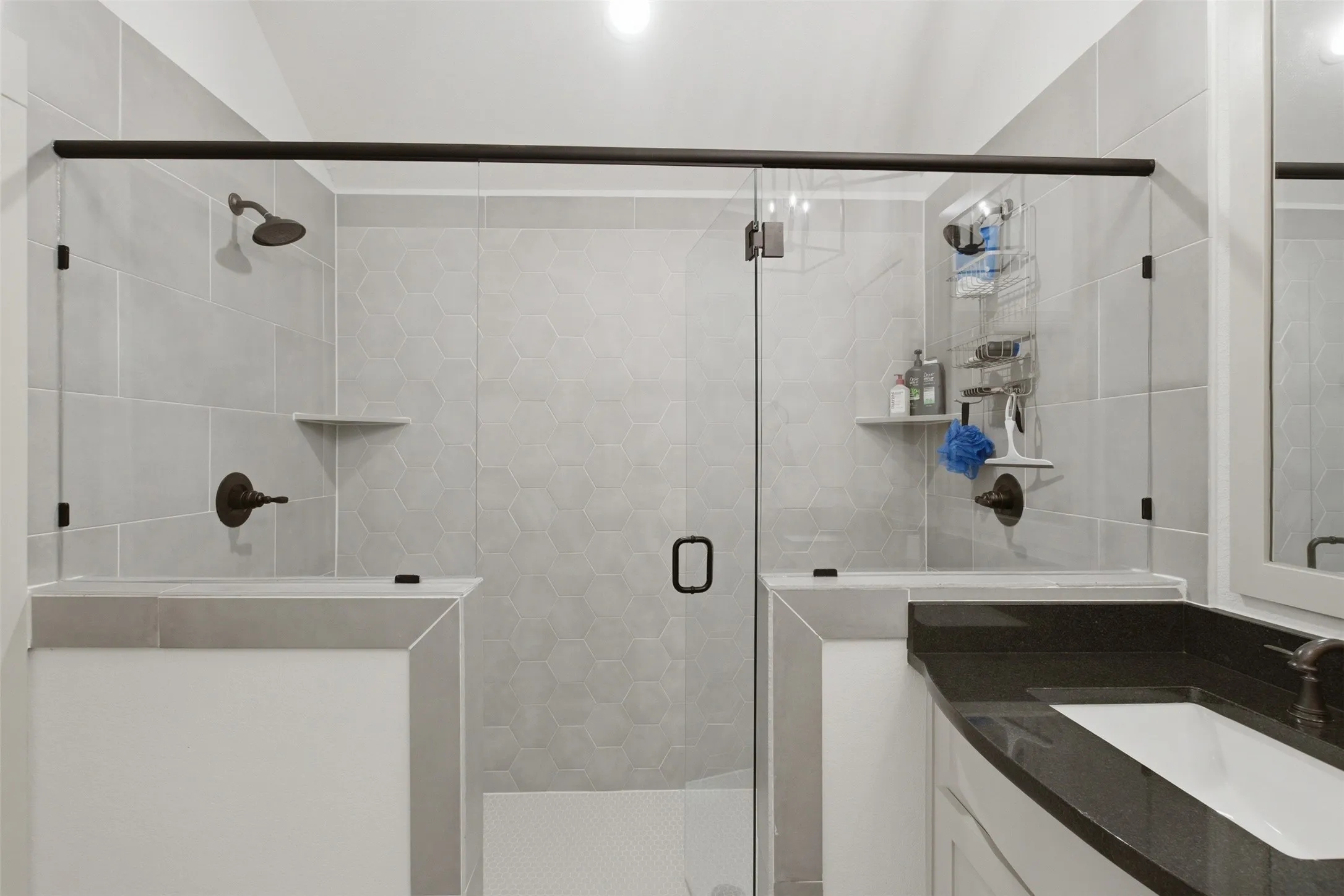 Spacious walk-in shower with clear glass enclosure and dark bronze hardware