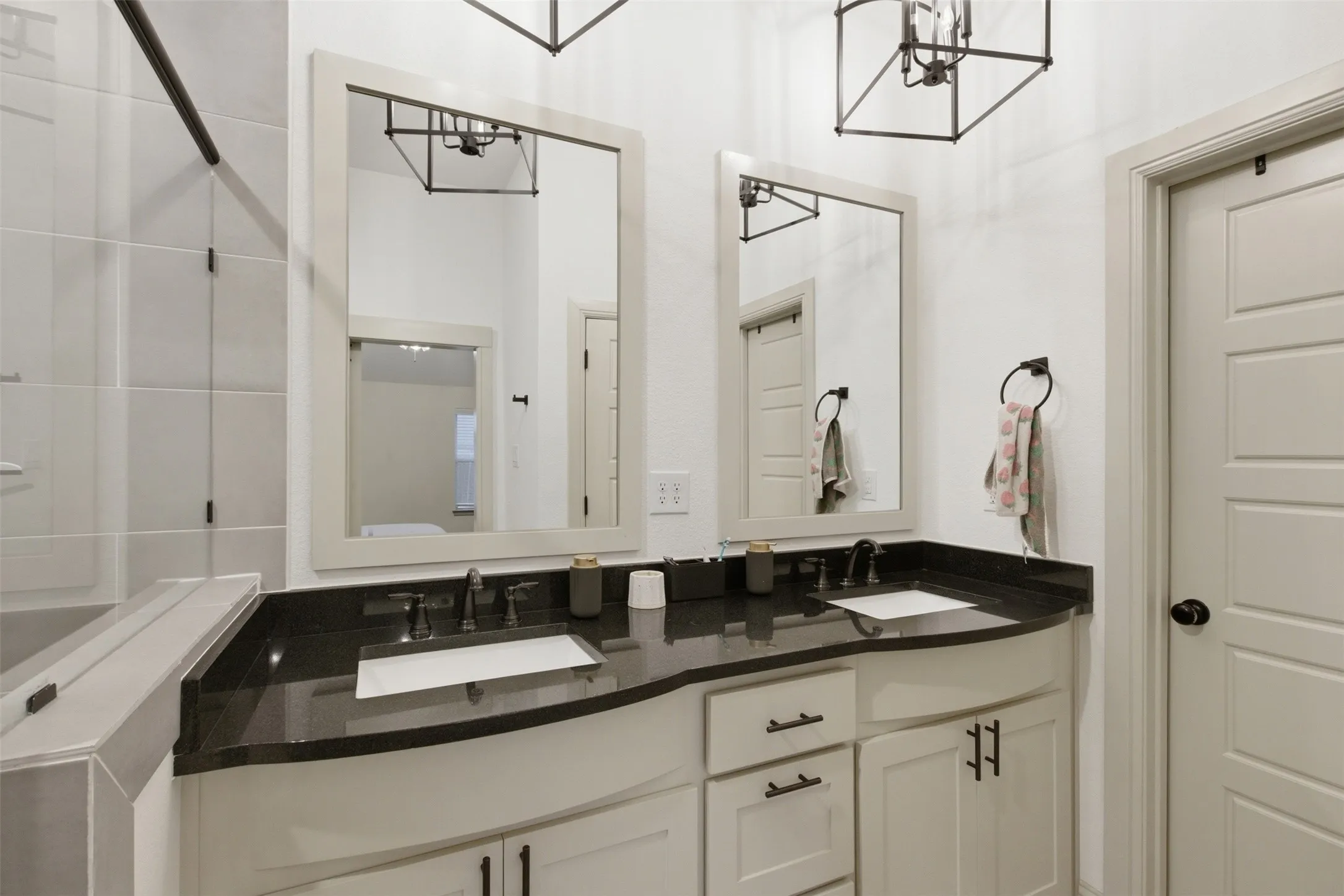 Dual vanity featuring undermount sinks, dark countertops, and matte black fixtures
