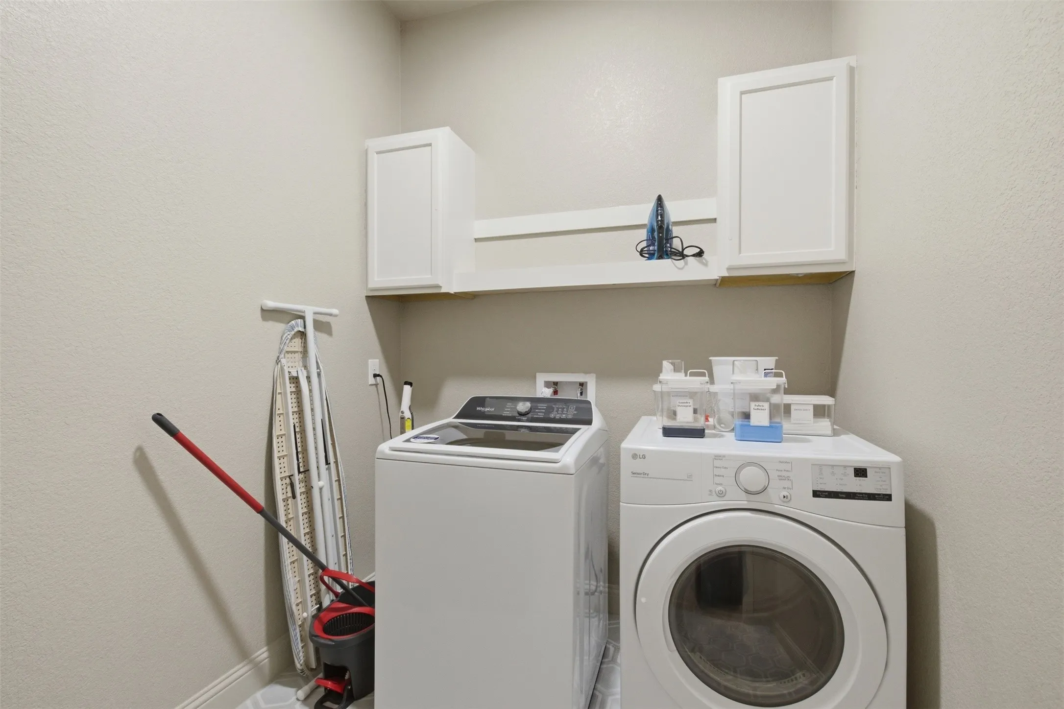 Dedicated laundry area featuring a shelf and two upper cabinets