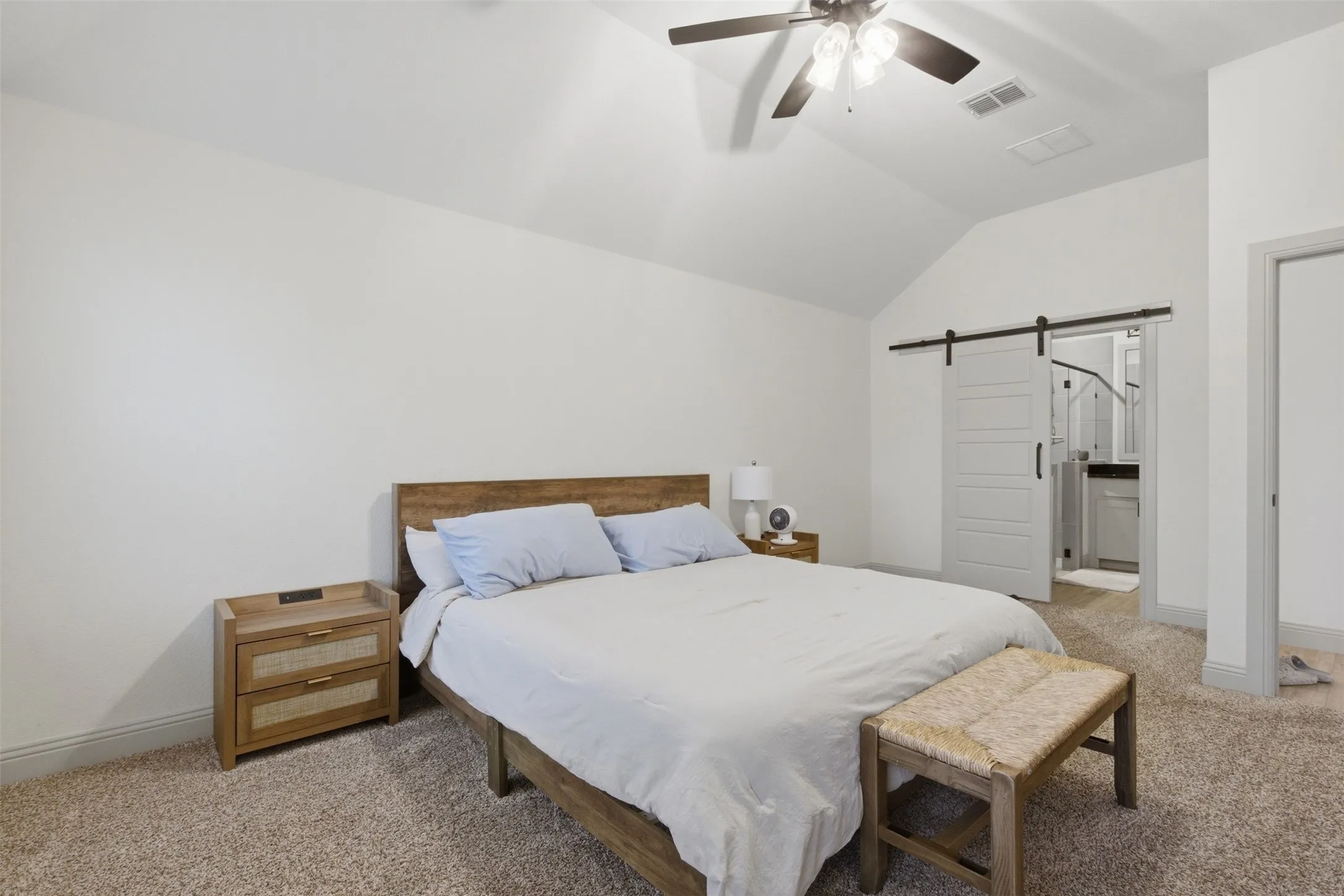Primary bedroom featuring a vaulted ceiling with a ceiling fan, a barn door leading to the Primary Bath area