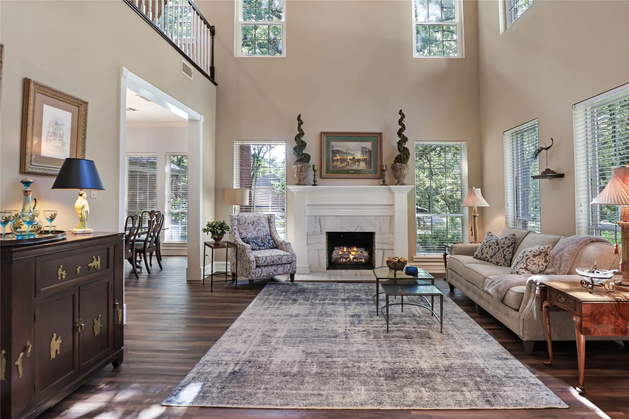 Living room with marble gas log fireplace, high ceiling and natural light