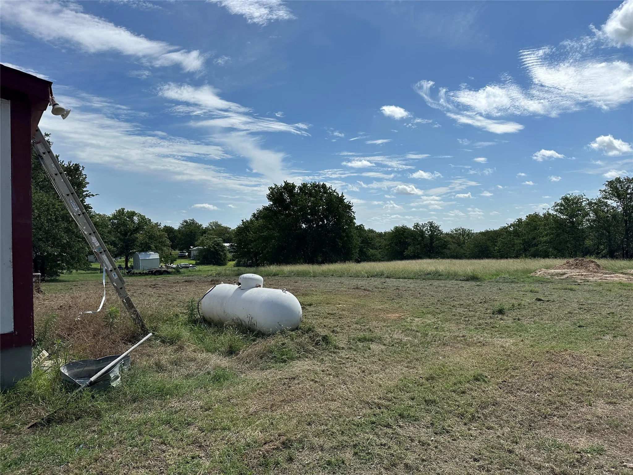 Expansive grassy terrain with mature trees bordering the property
