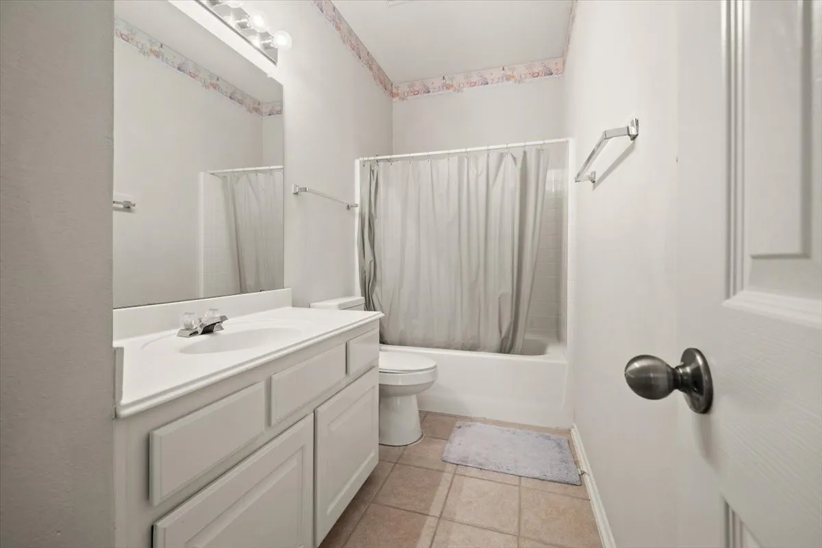 Bathroom featuring a white vanity with integrated sink, a large wall-mounted mirror, and a full bathtub with shower