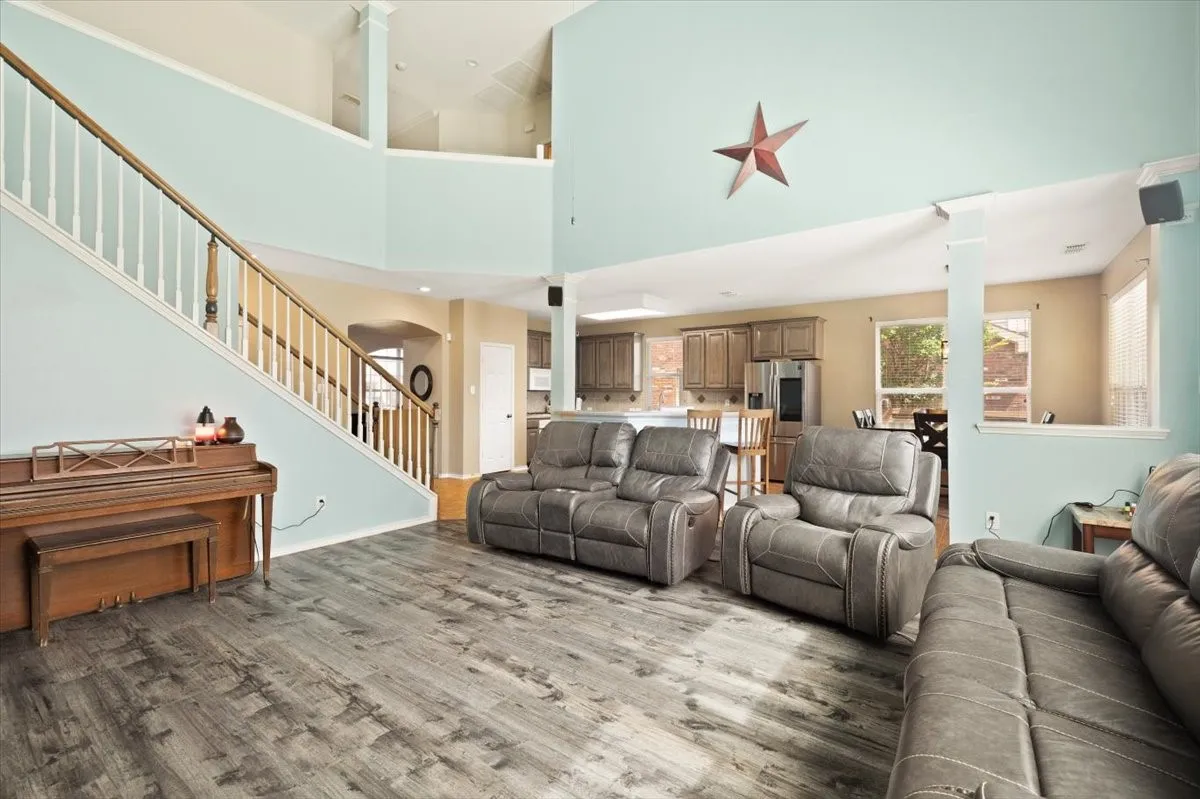 Vaulted living area featuring wood-finish flooring, a two-story ceiling, and an open-concept layout