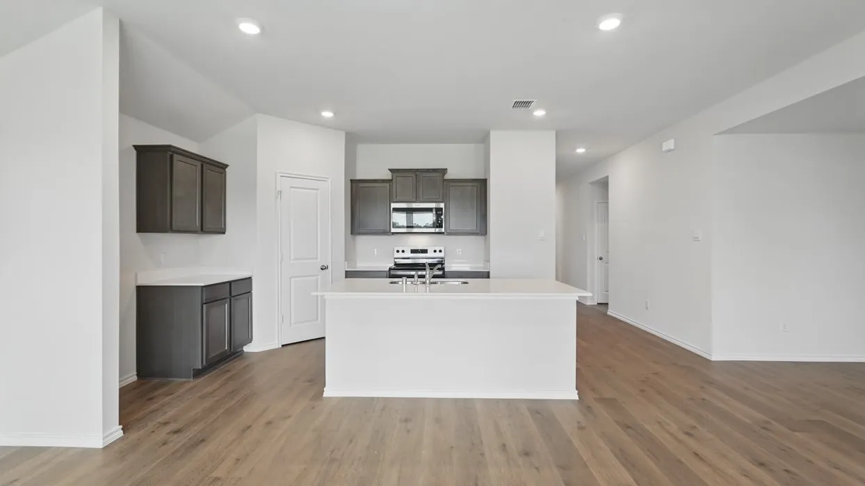Open-concept kitchen featuring a central island, recessed lighting, wood-finish flooring, dark cabinetry, and white countertops