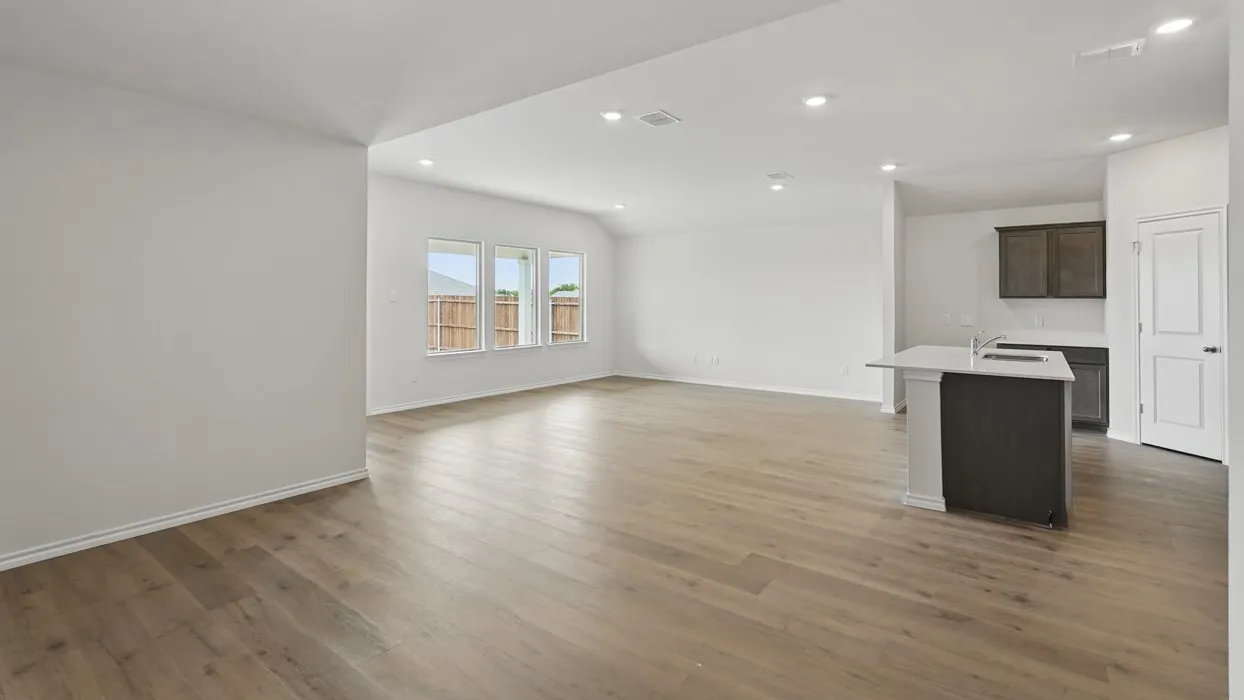 Open-concept living space featuring wood-finish flooring, recessed lighting, and a kitchen island with an undermount sink
