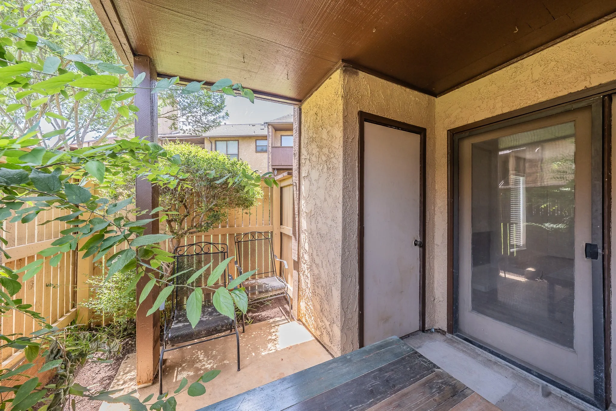 Private outdoor patio area with concrete flooring, accented by a sliding glass door and exterior storage.