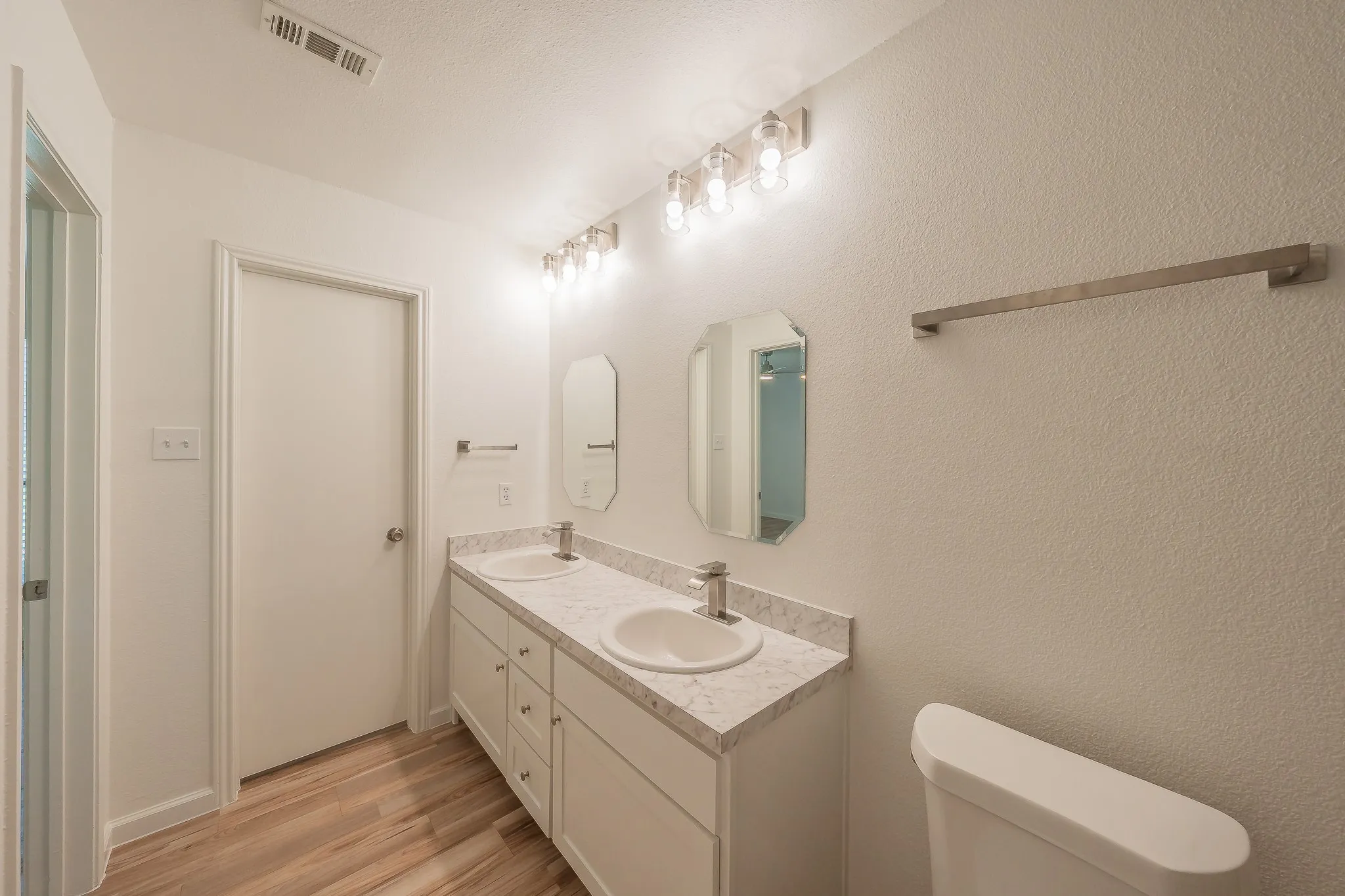 Bathroom featuring a dual vanity with new cabinetry, sinks, faucets and lighting.