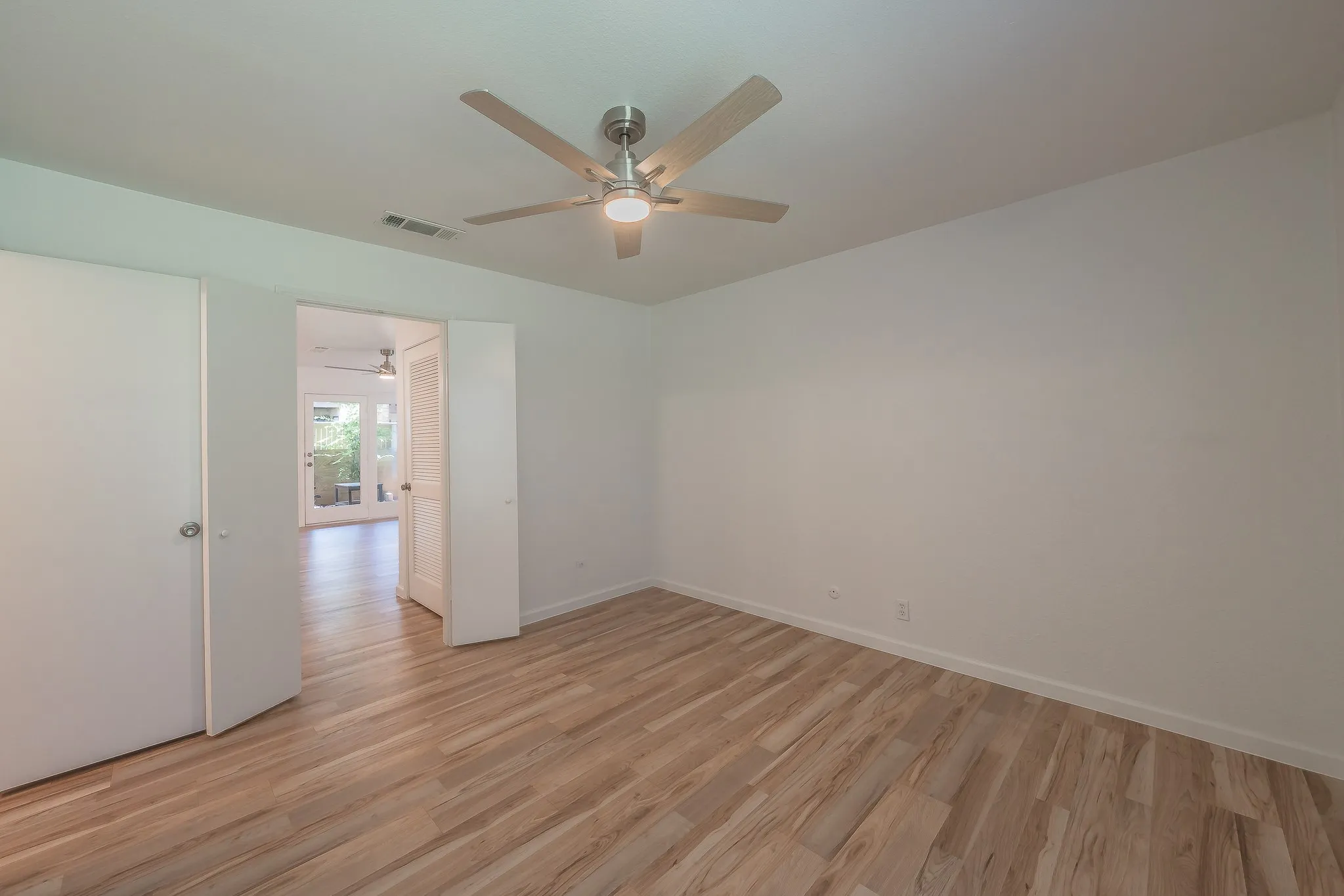 Spacious room featuring wood-finish flooring and a contemporary ceiling fan