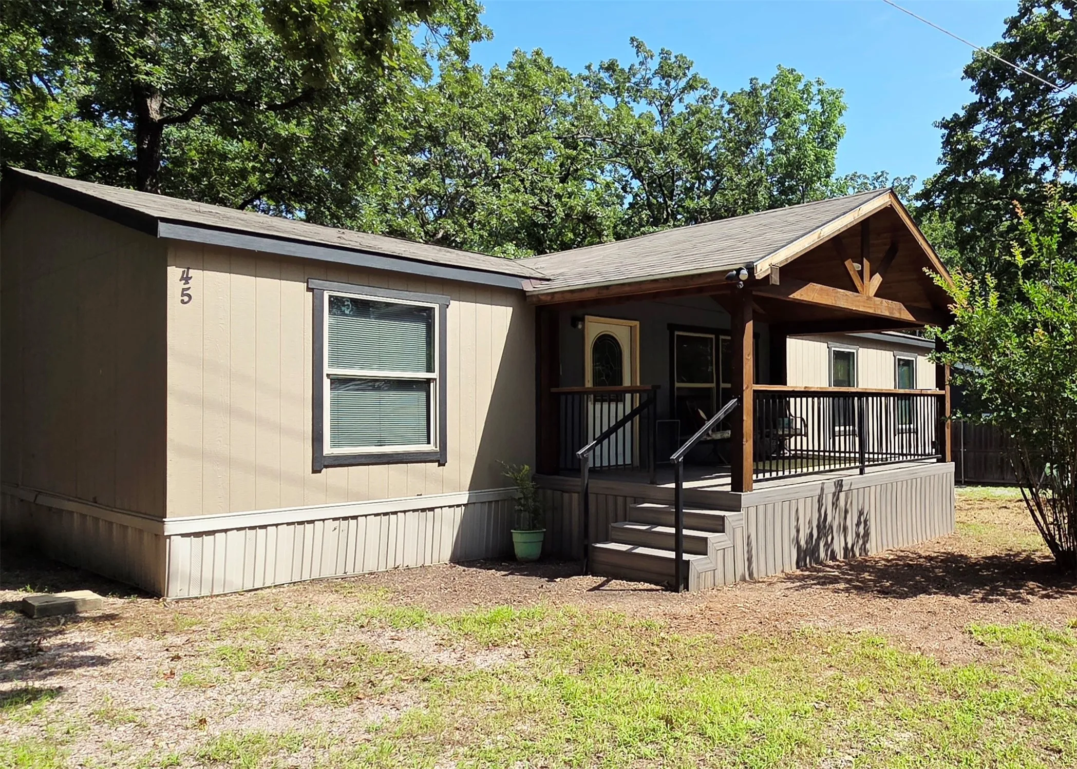 Exterior featuring a covered porch with wood accents, dark railings, and multi-level steps