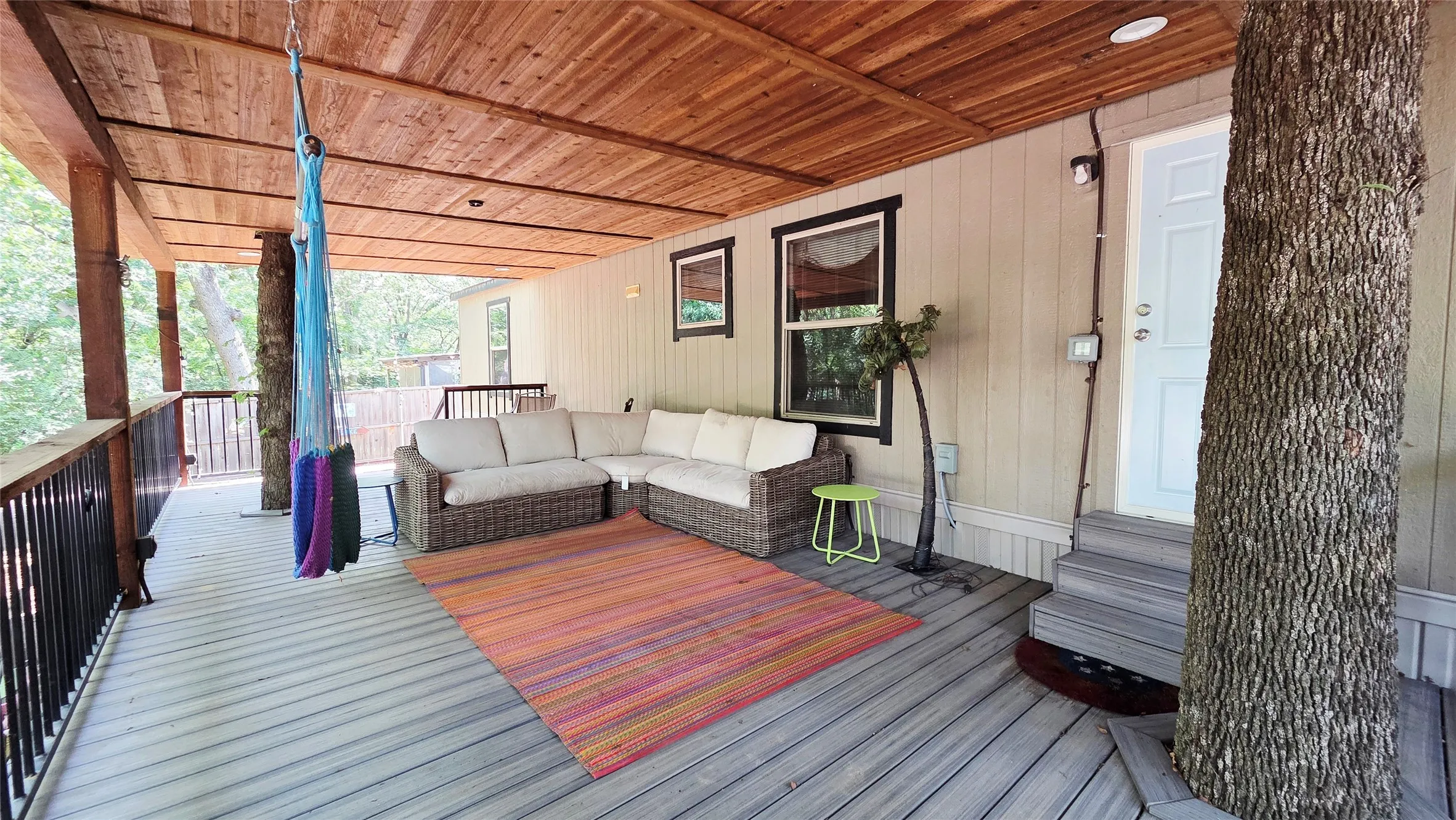 Spacious covered deck featuring a natural wood plank ceiling, light-colored vertical siding, and grey wood-finish flooring