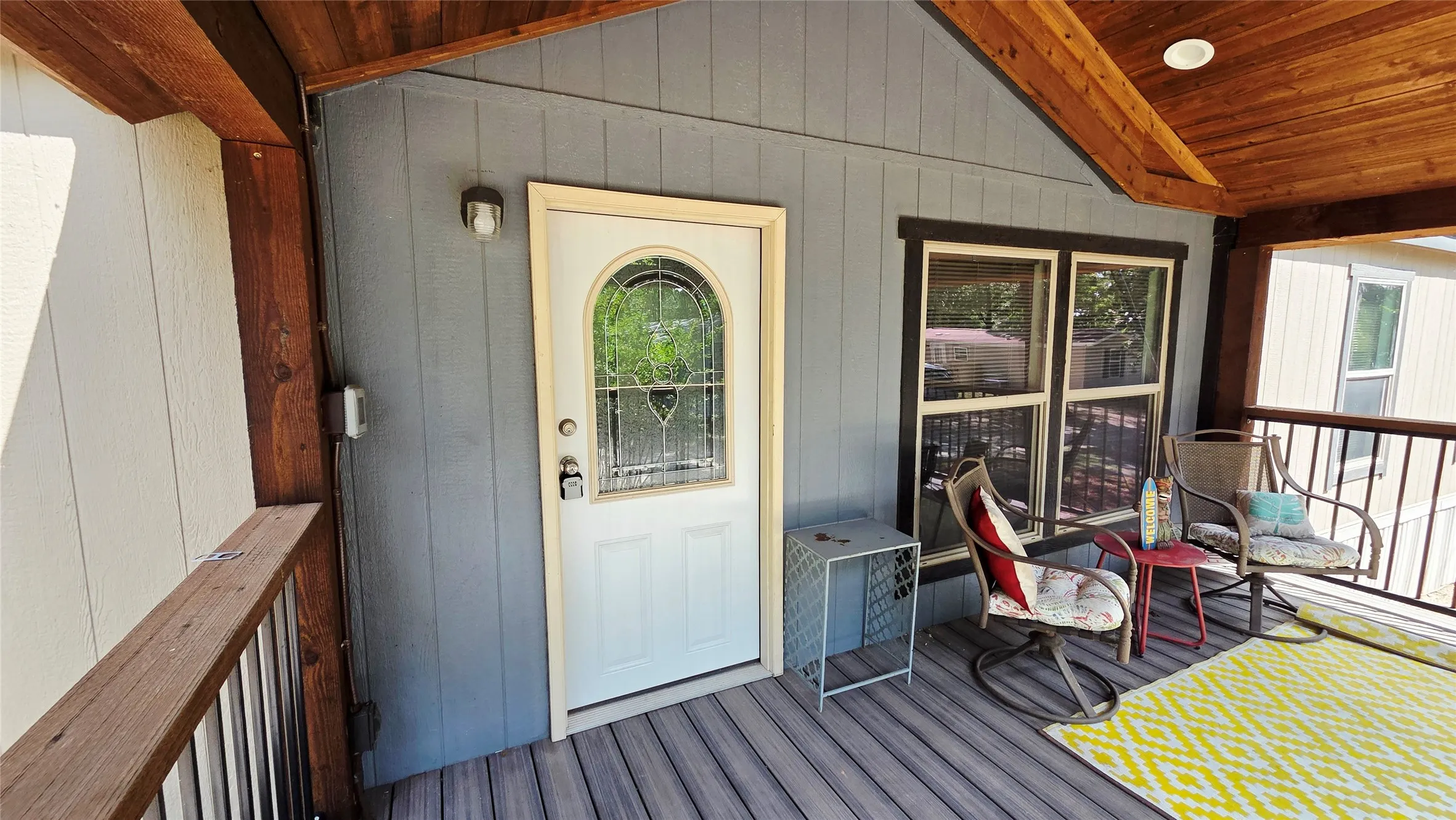 Covered porch with wood-finish ceiling, gray siding, and composite decking