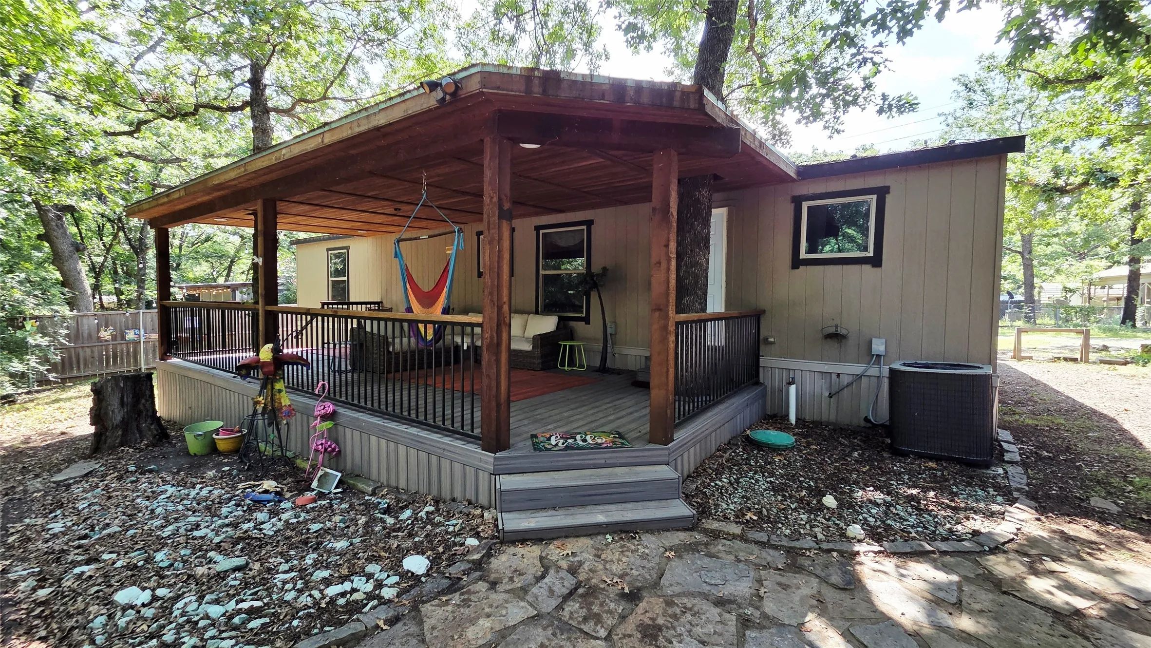 Covered porch with exposed wood beams, composite decking, and black metal railings
