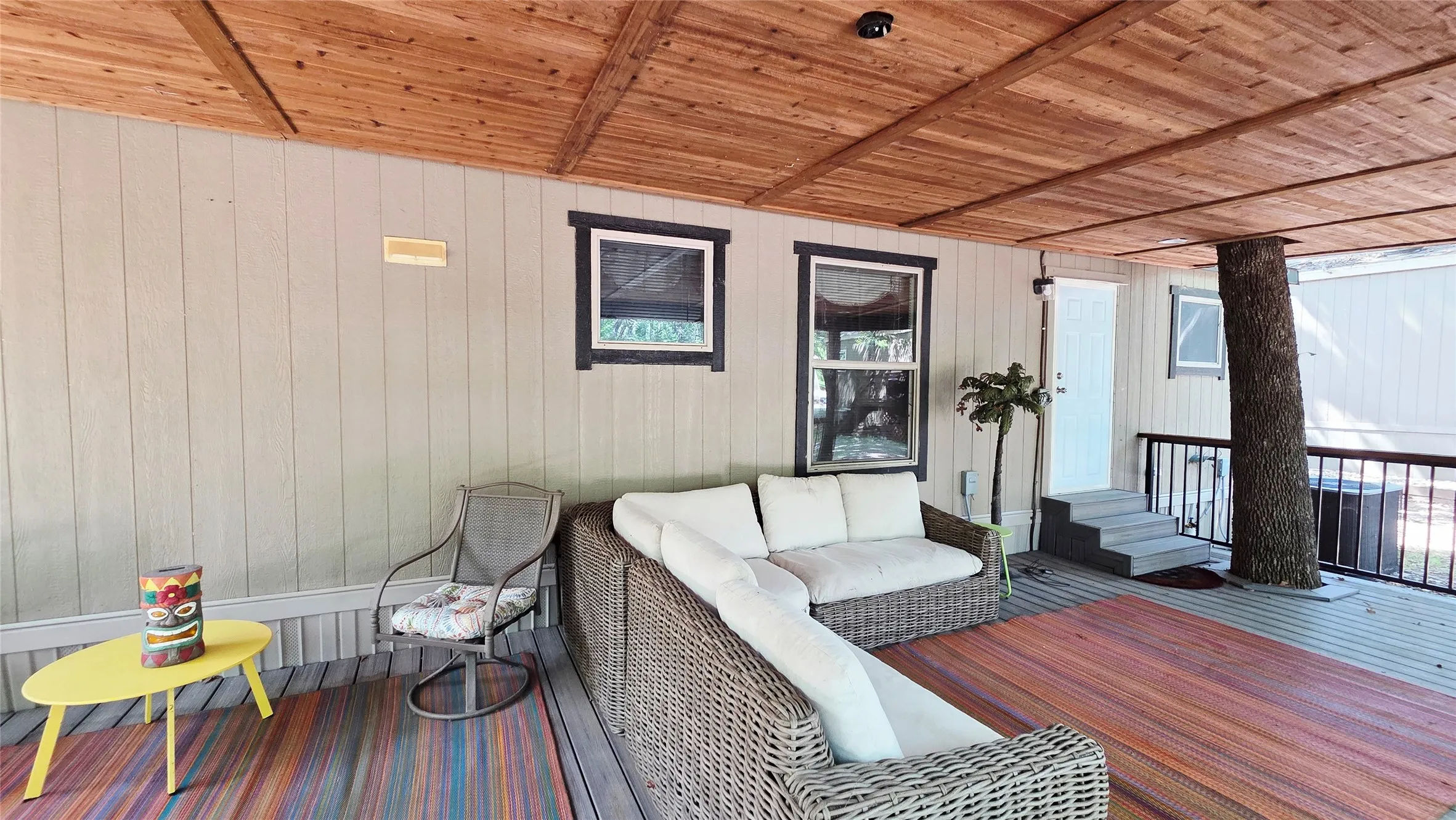 Spacious covered deck featuring wood-finish ceiling, gray siding, and dark trim windows