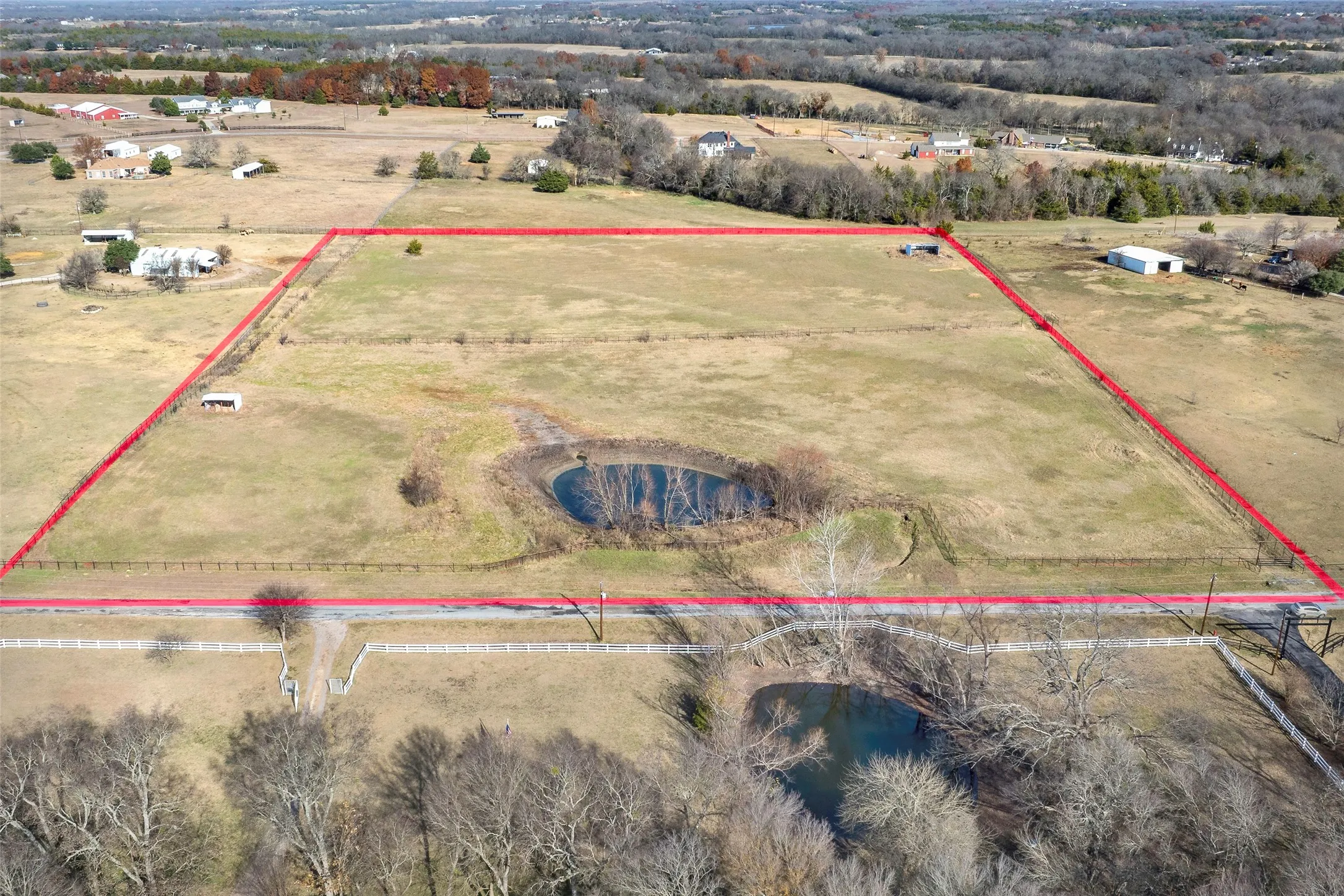 Expansive land parcel featuring open fields, a dedicated pond, and direct road frontage