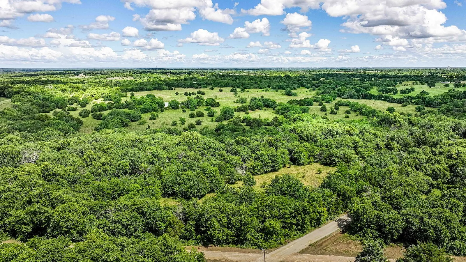 Expansive green landscape featuring varied tree coverage and open grassy areas