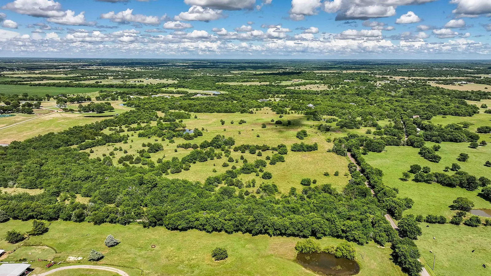 Expansive rural landscape featuring extensive green acreage and mature tree coverage