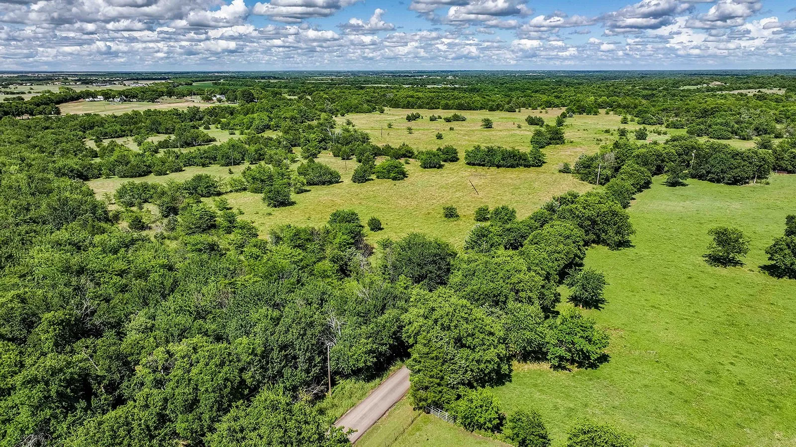 Expansive rural acreage featuring a mix of mature trees and open grasslands