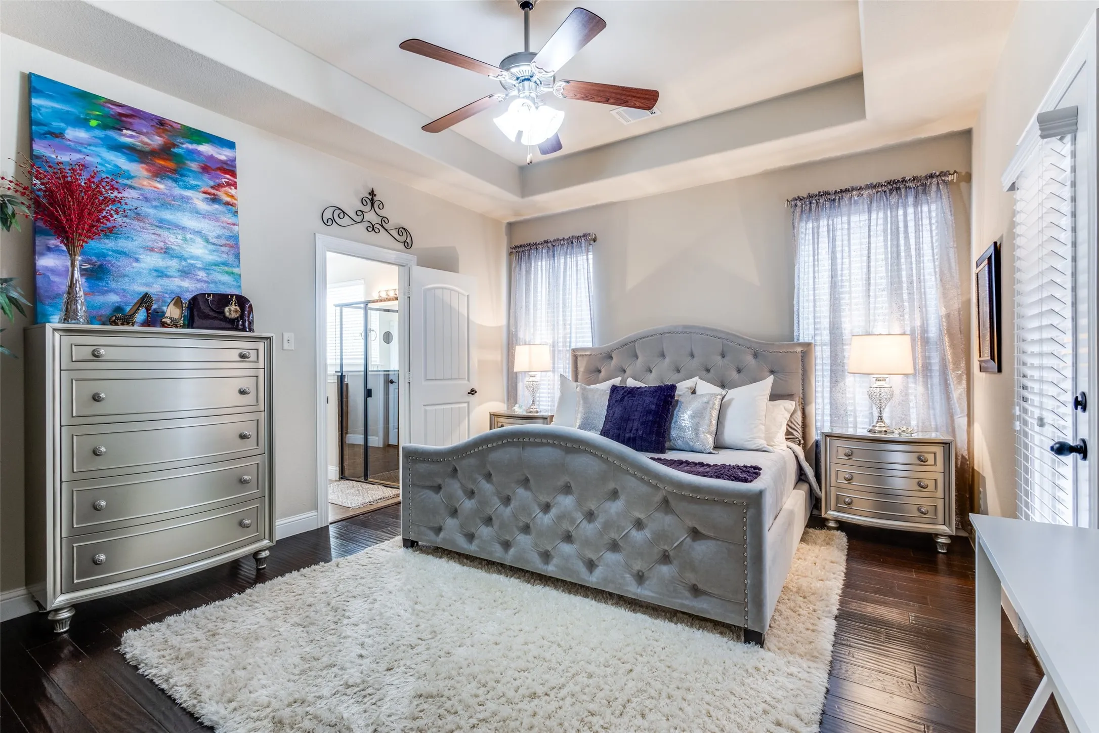 Master bedroom with door to side patio, wood flooring and ceiling fan