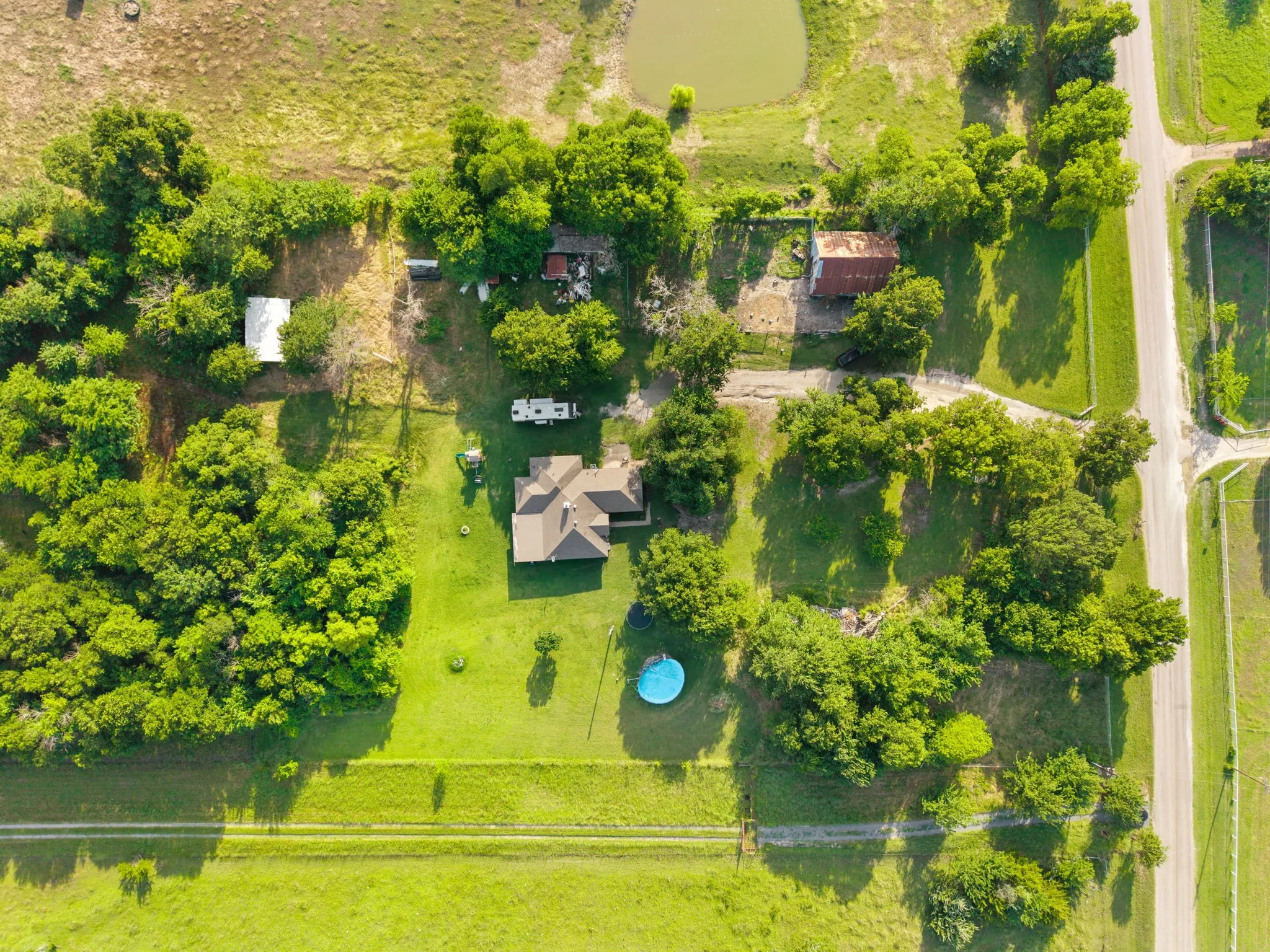 Expansive grounds featuring a main residence with a gabled roof, a vibrant green lawn, and mature trees