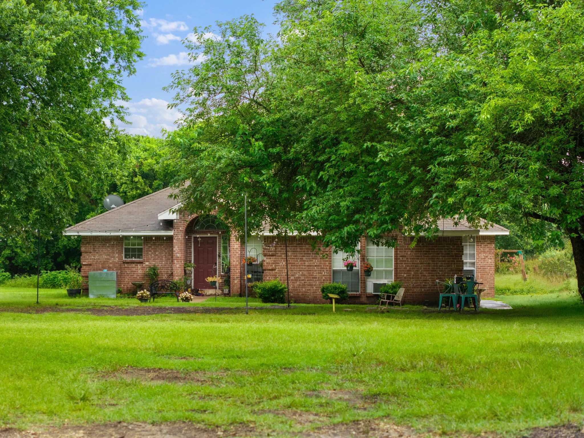 Brick exterior residence featuring an arched entryway, gabled roof, and multiple windows