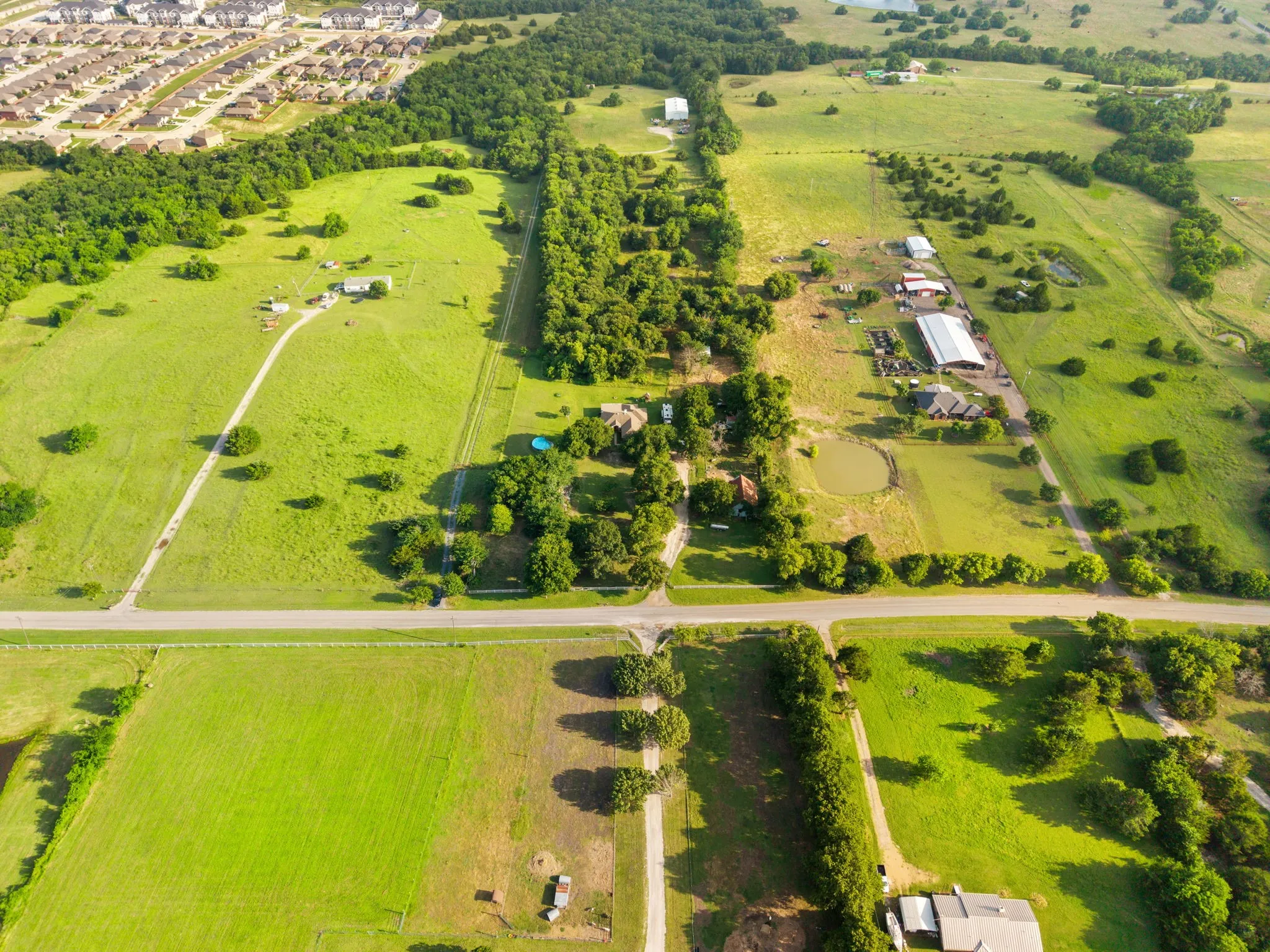Expansive aerial perspective showcasing a large land parcel with a paved road frontage