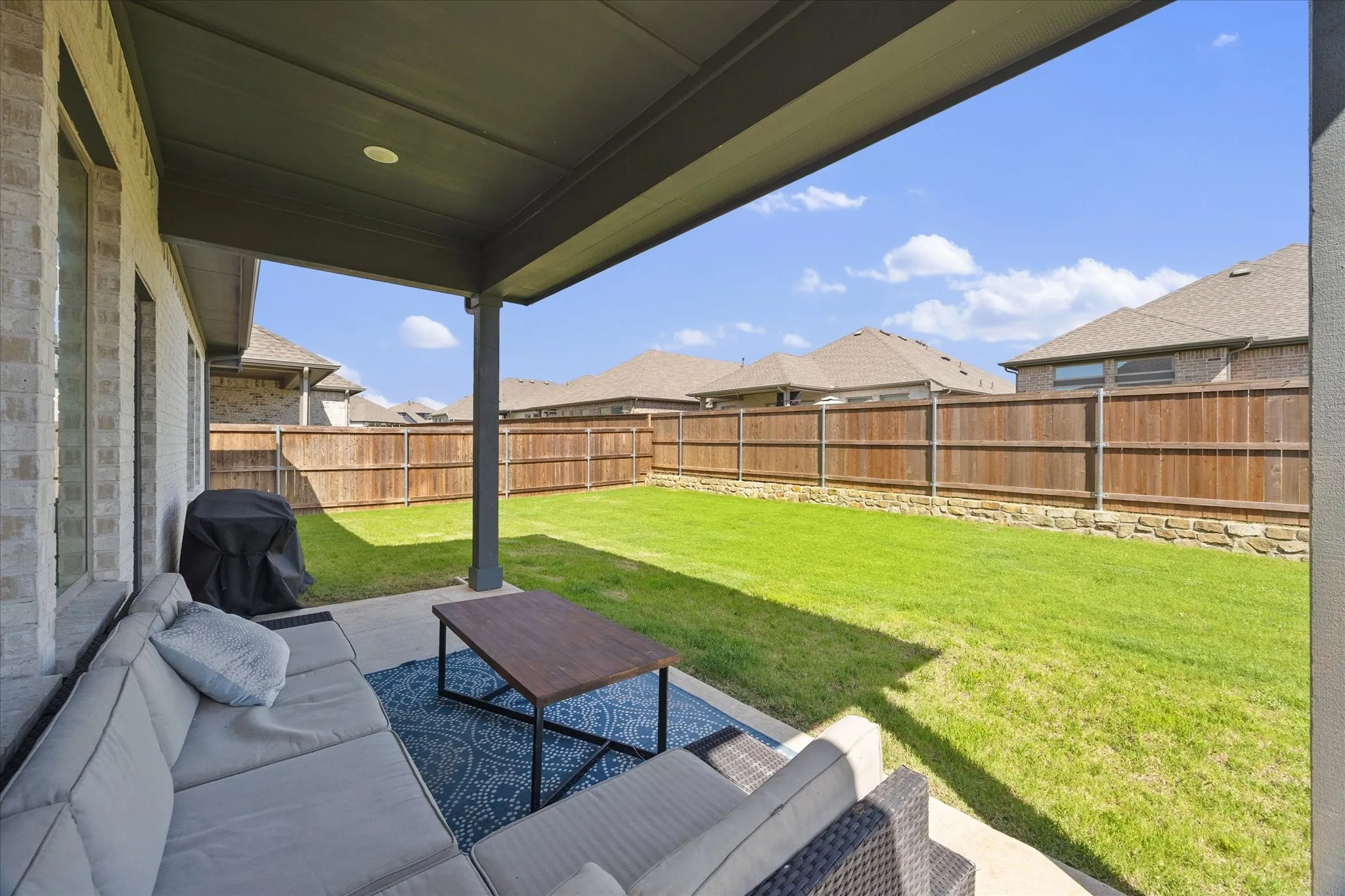 Covered patio overlooks fenced backyard