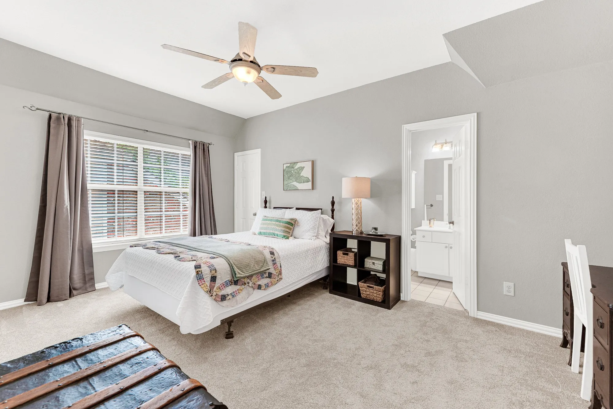 A wide window illuminates the soft palette of this space, while a private ensuite doorway ensures absolute convenience. Guests will love waking up to a bright, peaceful morning before starting their day in total privacy