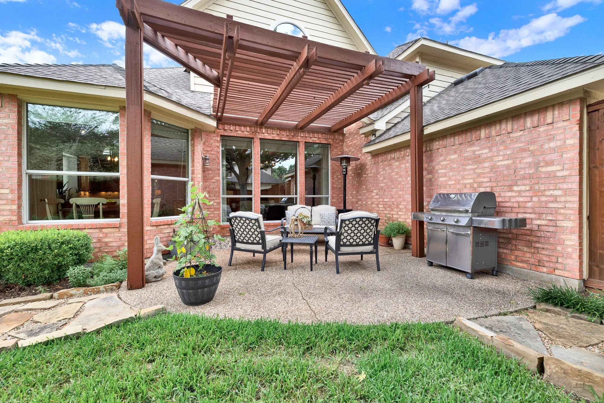 The sturdy columns of the architectural pergola frame a spacious outdoor living area nestled directly against the warm brick exterior. Settle in for a relaxed evening of storytelling and stargazing as the daylight fades into a cool twilight.