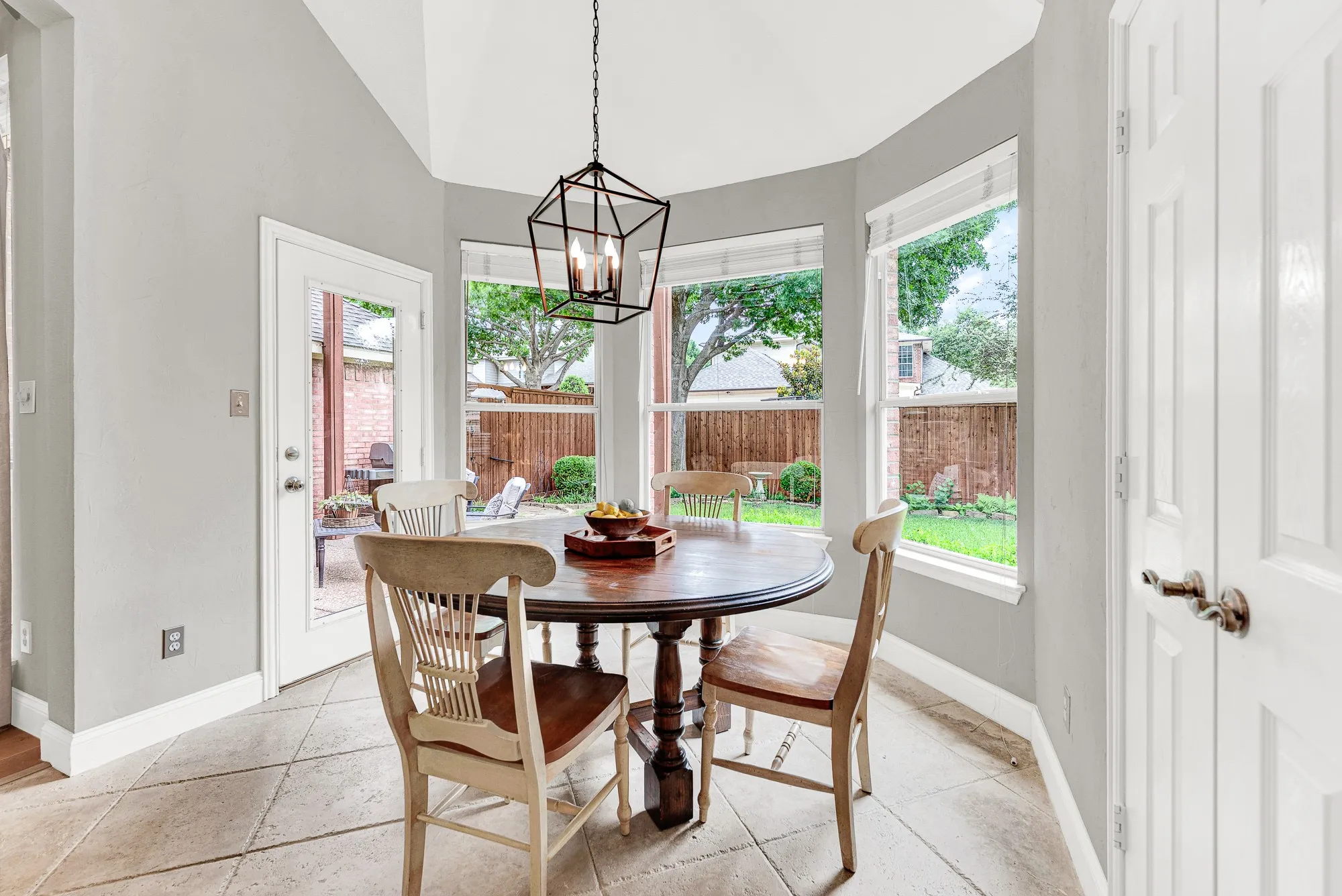 A curved bay of windows wraps the breakfast nook on three sides, filling the vaulted octagonal space with treetop views and backyard greenery all day long. Step out the back door to the patio, or just sit here and enjoy the view — both feel equally right.