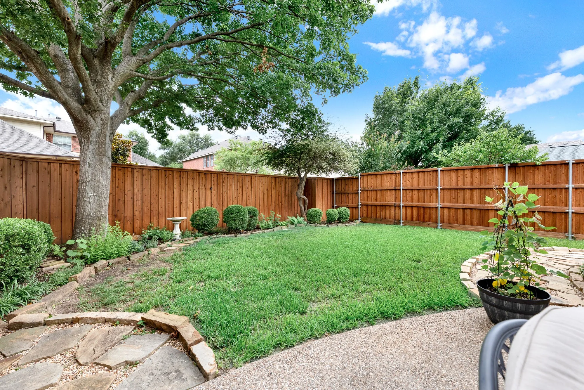The deeply stained privacy fence wraps around a beautifully manicured lawn, creating a secure, hidden oasis framed by neatly edged stone borders. Imagine playing a game of catch with family or watching a pet run freely on a sunny afternoon.