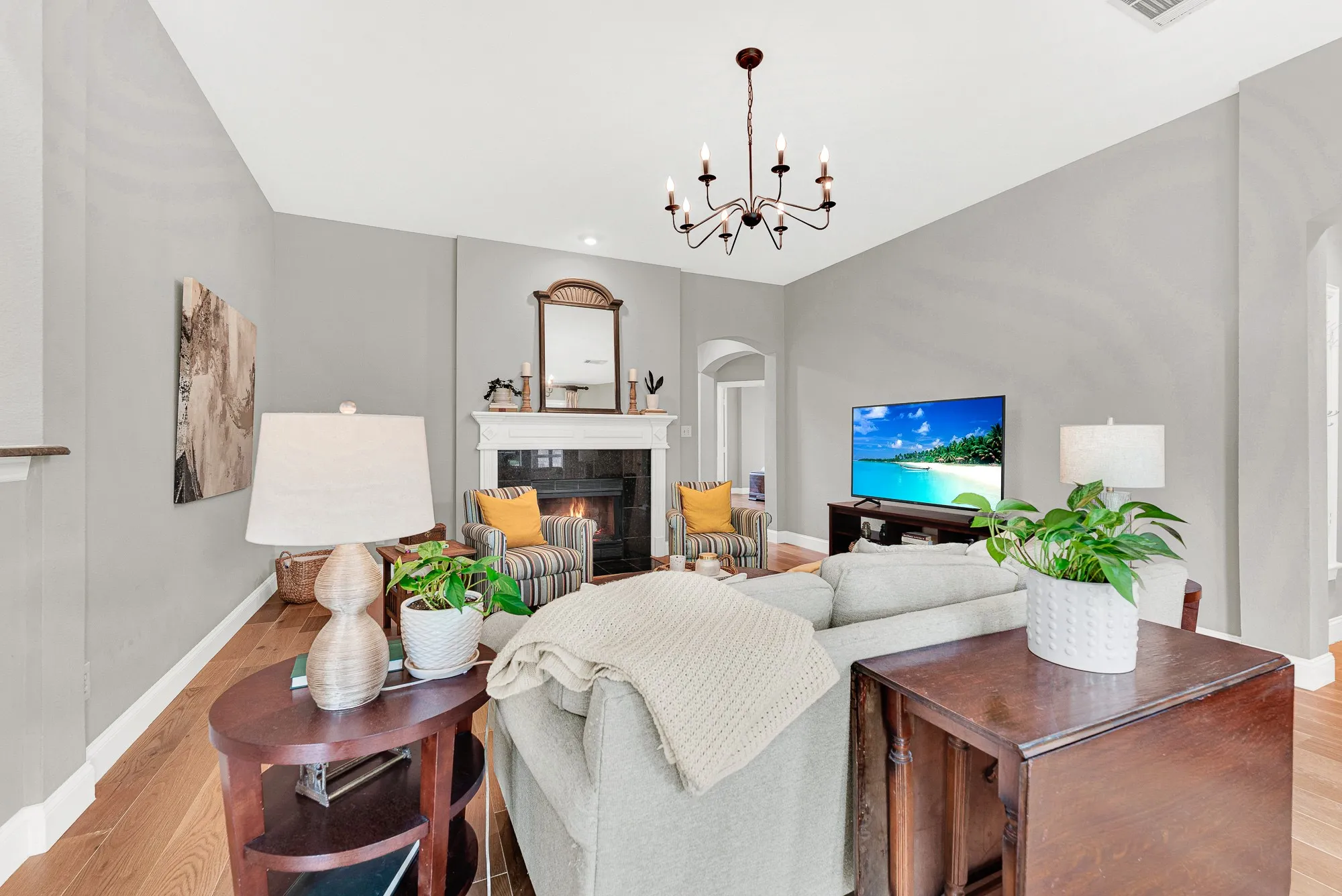 A classic white-surround fireplace with black tile hearth anchors the room as a warm focal point, framed by an arched passageway that keeps the space connected to the rest of the home. Light that fire on a cool evening and this room becomes the only place anyone wants to be.