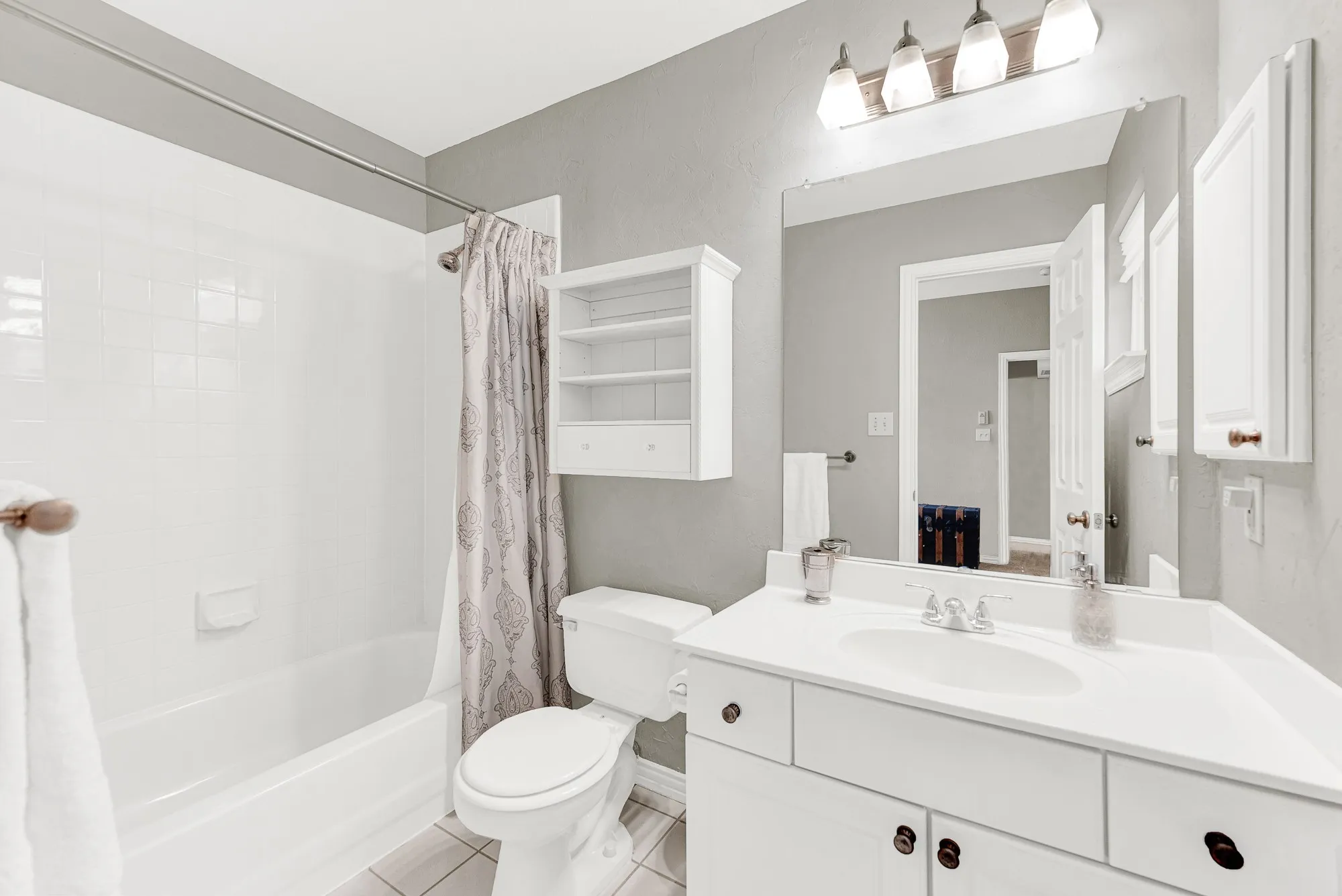 Crisp white tile and cabinetry bounce the vanity light, maximizing the bright and airy feel of this private bath. Visitors can comfortably unpack their essentials and enjoy a refreshing, hassle-free morning routine.
