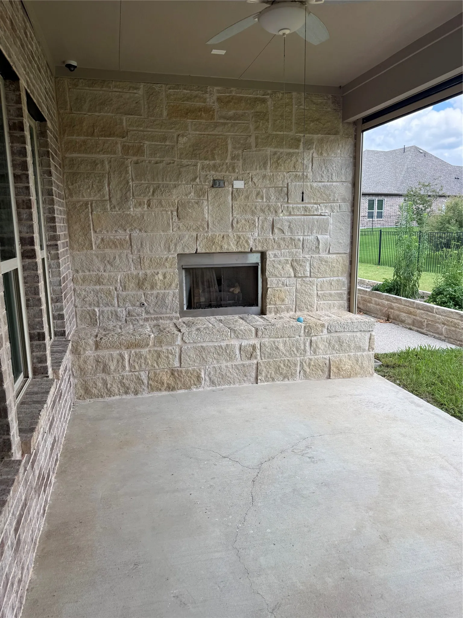 Covered patio with a stone-clad fireplace and hearth