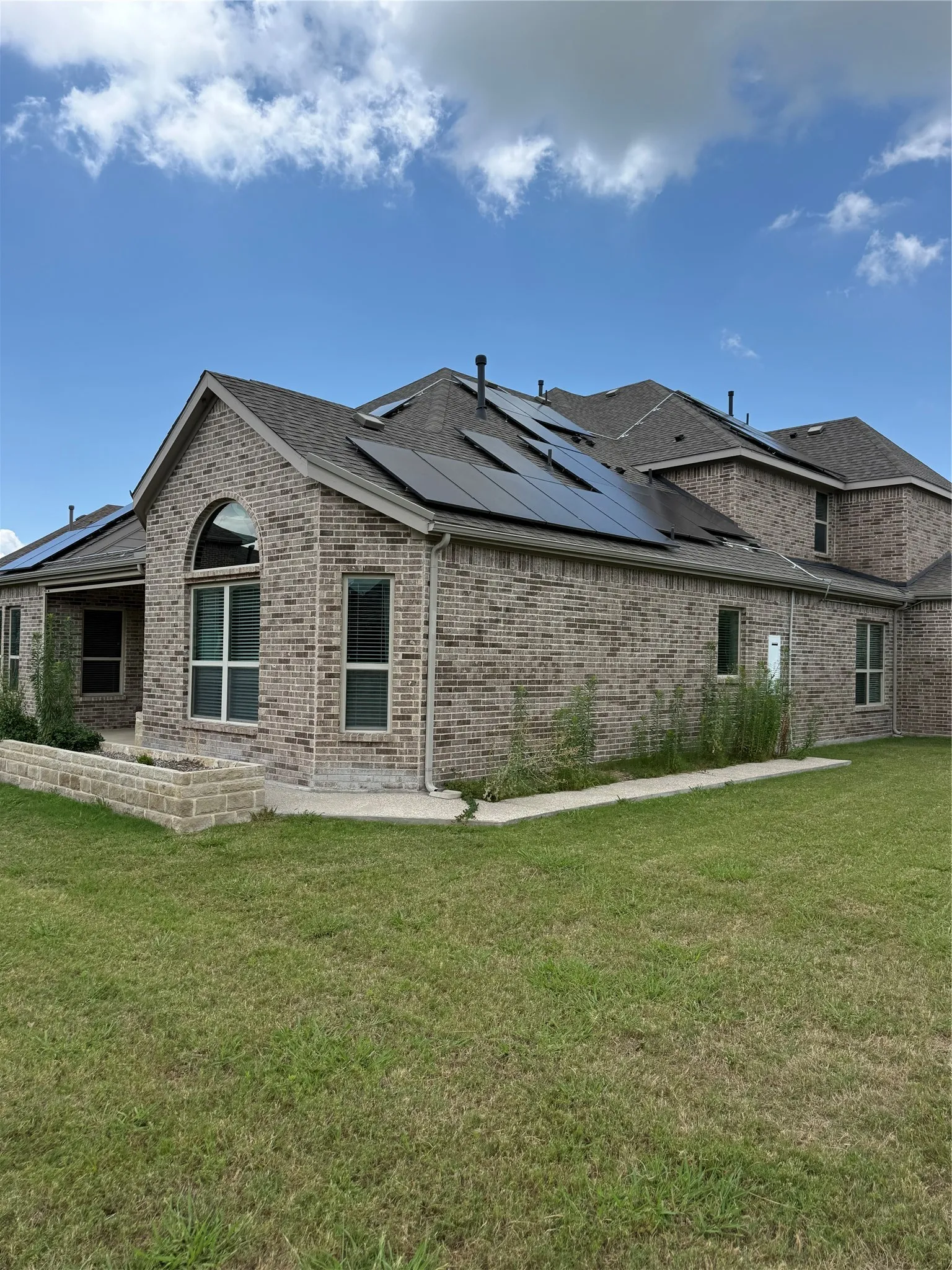 Brick exterior featuring multiple rooflines, an arched window, and several solar panels