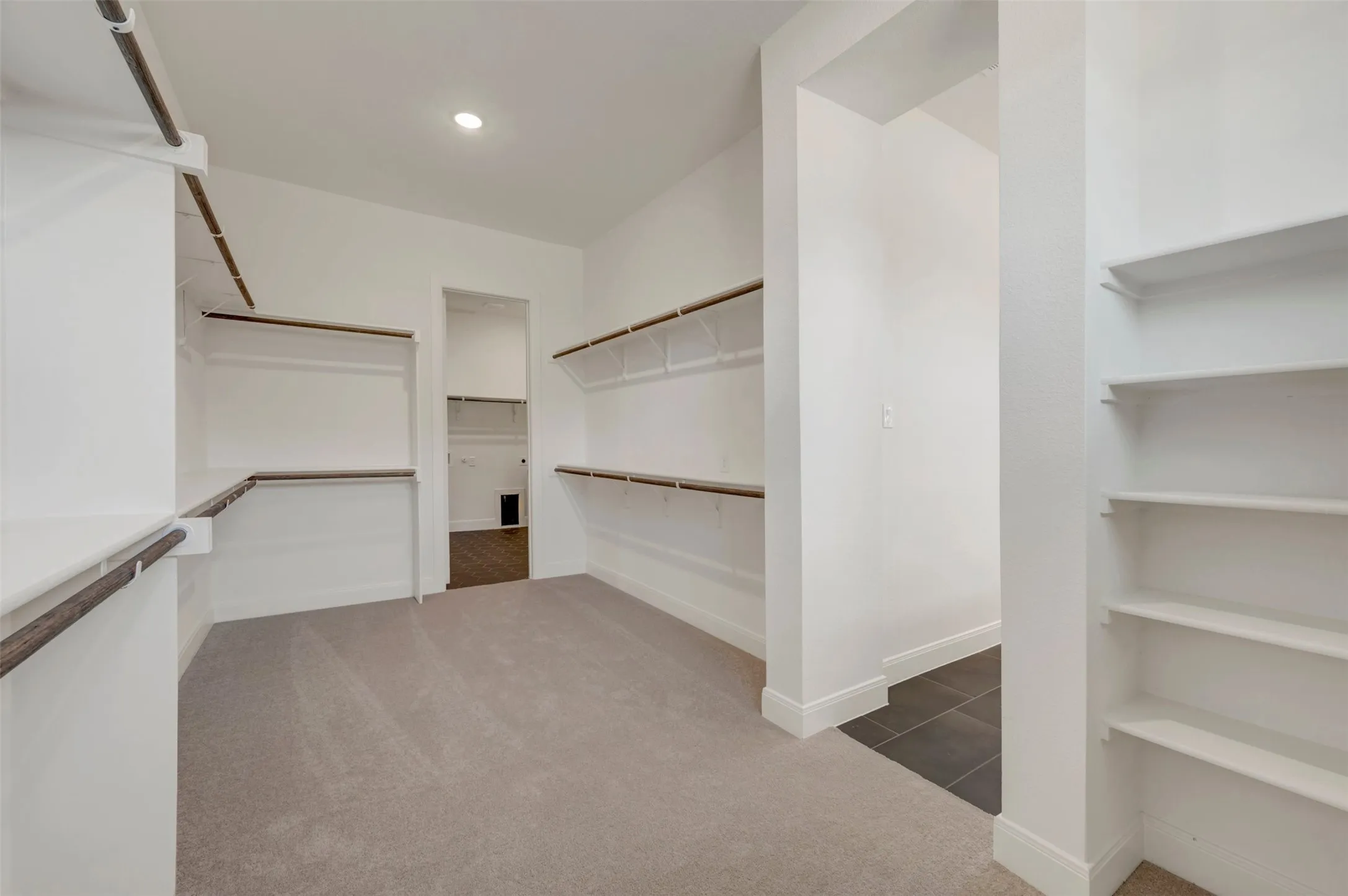 Spacious walk-in closet featuring built-in shelving, hanging rods, and carpet flooring