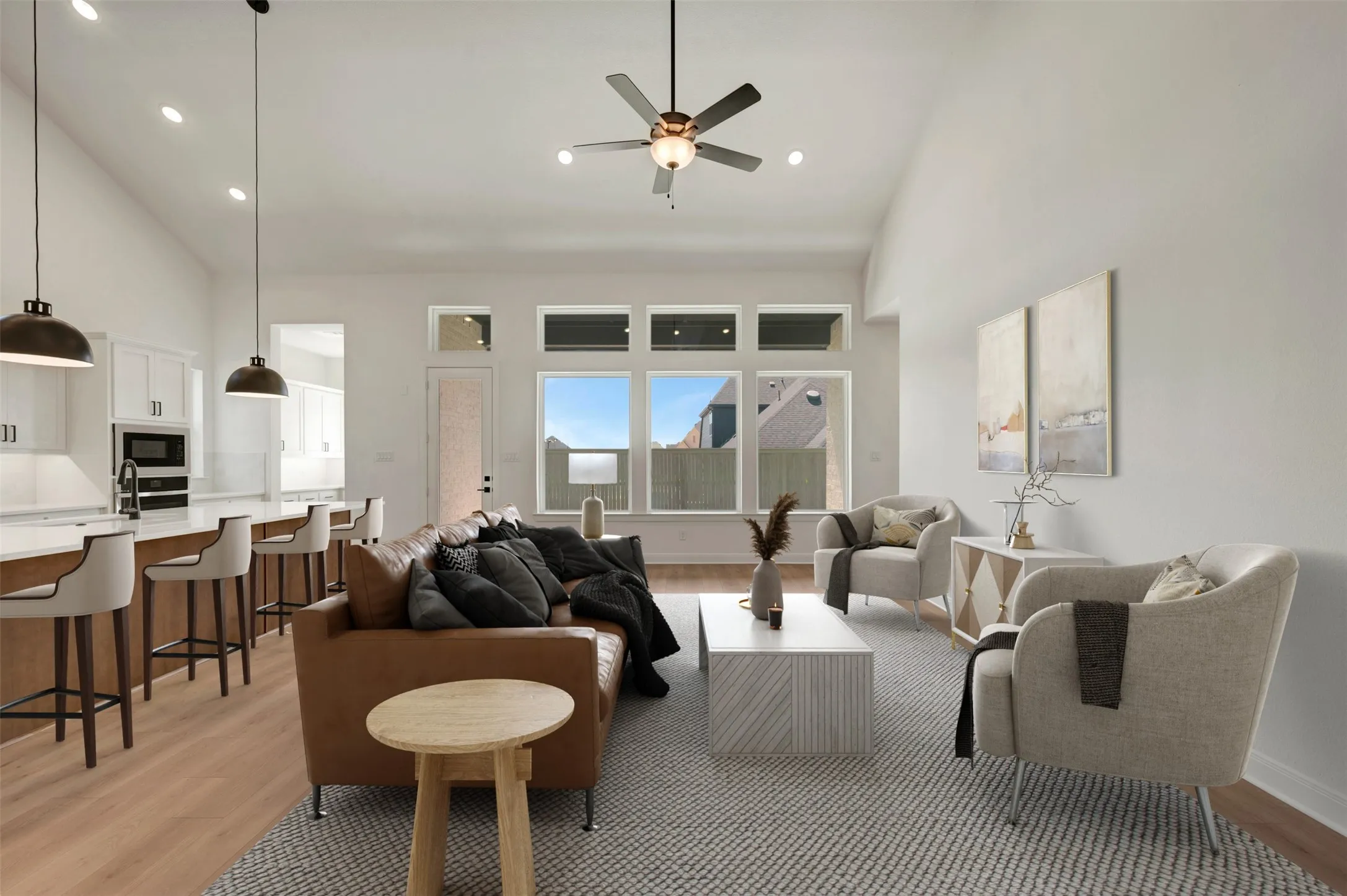 Open-concept living area featuring high vaulted ceilings, recessed lighting, wood-finish flooring, a ceiling fan, and large windows