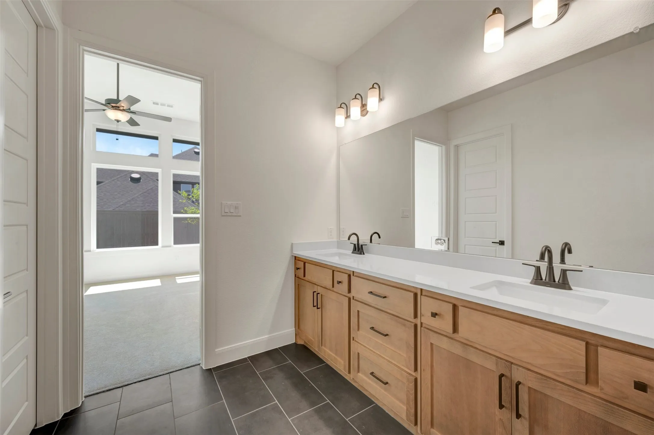 Dual vanities with white countertops, wood-finish cabinetry, and dark bronze fixtures